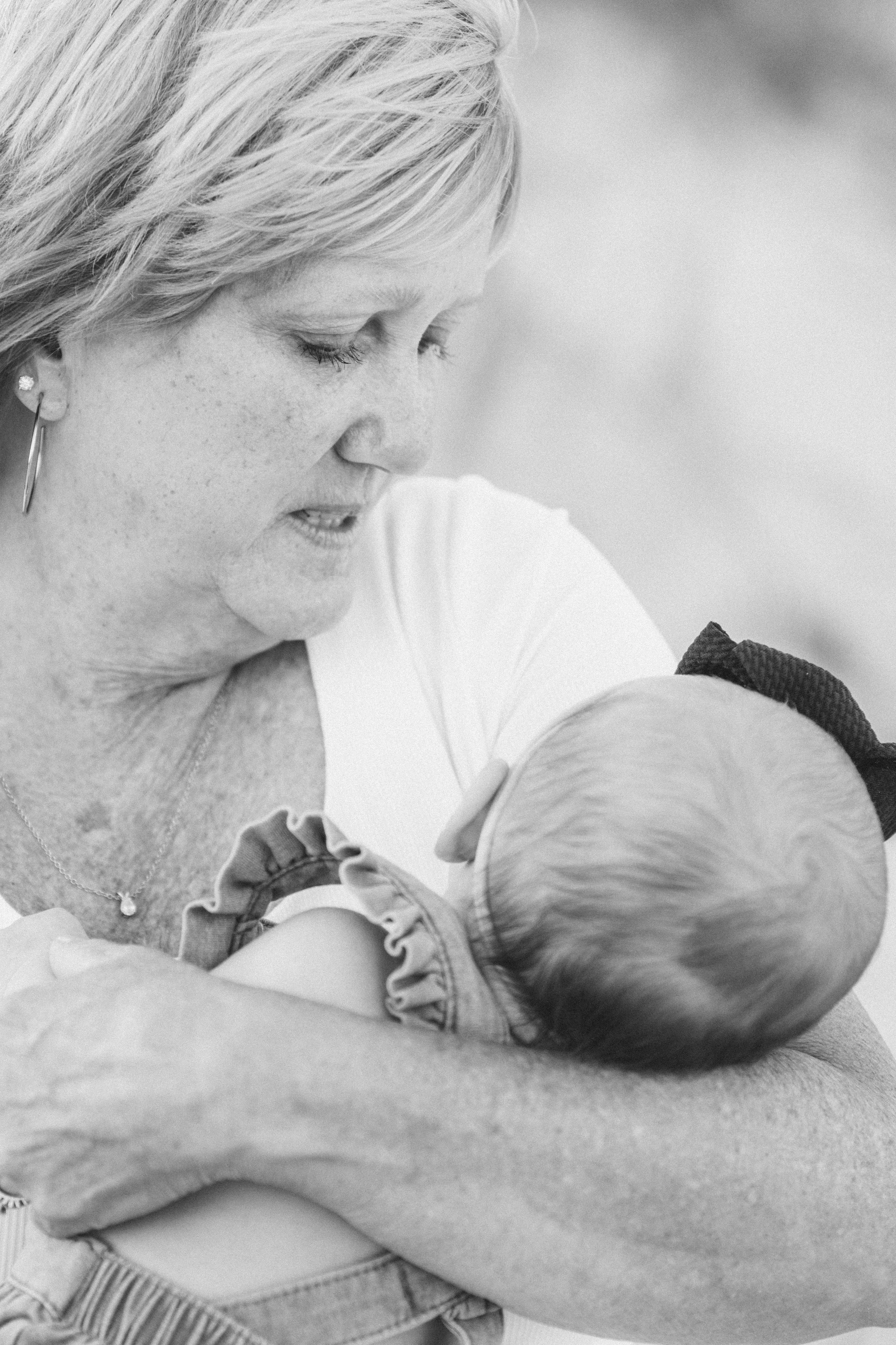 A woman lovingly holds a baby close to her chest, gazing at the baby with affection.