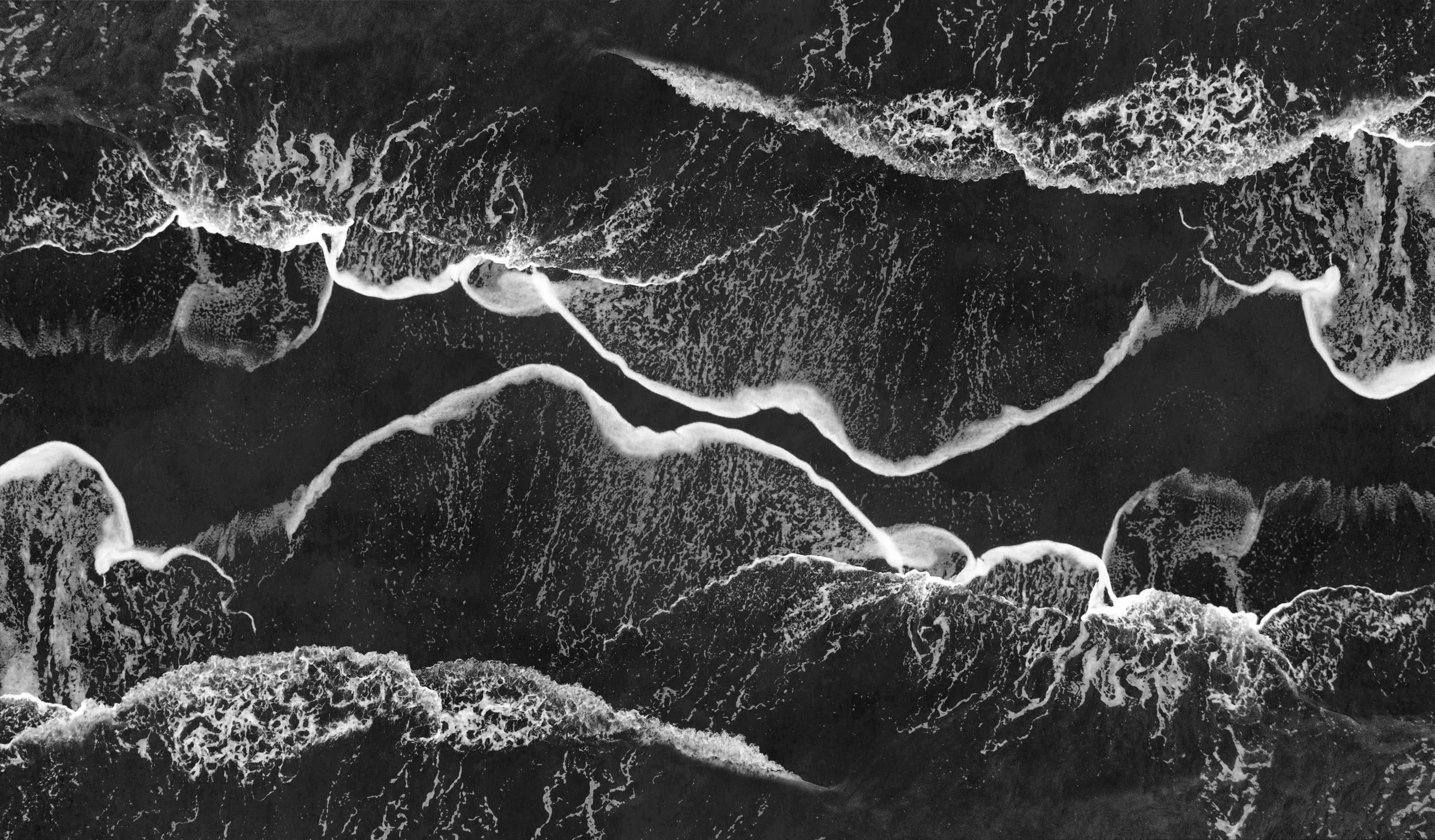 Black and white aerial ocean wave patterns — abstract coastal imagery used in Lumminum’s brand design.