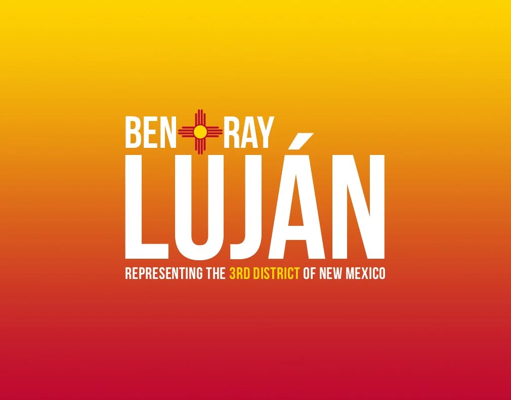 Campaign poster with the name 'Ben Ray Luján,' featuring the New Mexico state flag modified into a rising sun over a red and yellow background. Text states 'Representing the 3rd District of New Mexico.'