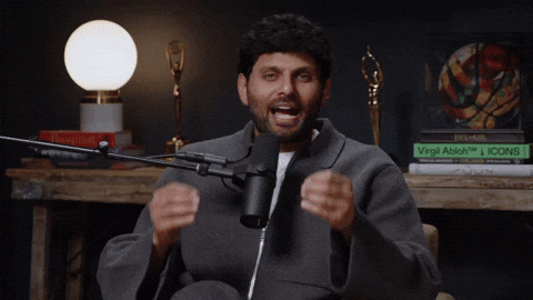 A man speaking passionately into a microphone during a podcast or interview in a studio.