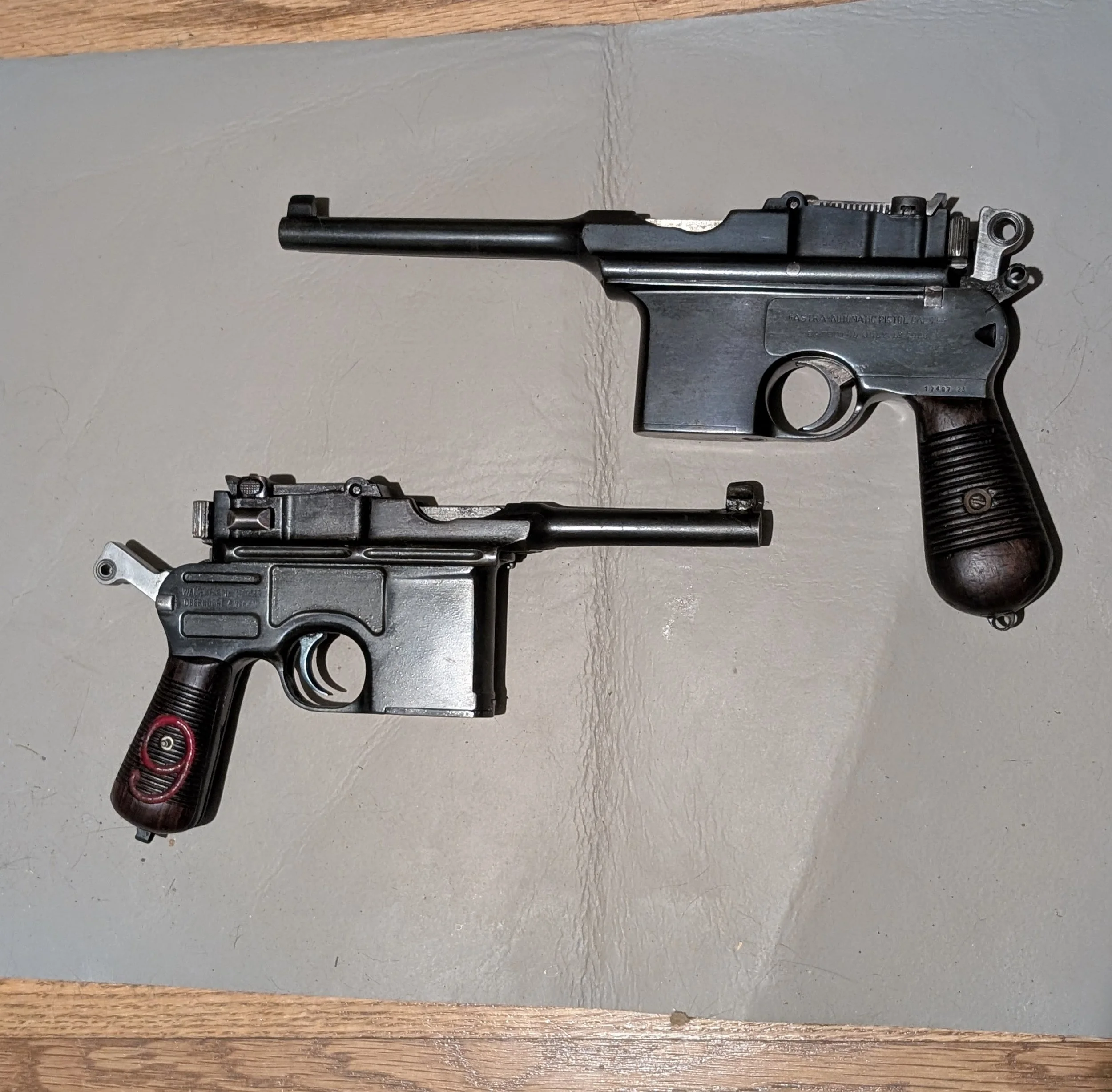 Two vintage firearms, one rifle and one submachine gun, laid on a gray surface.