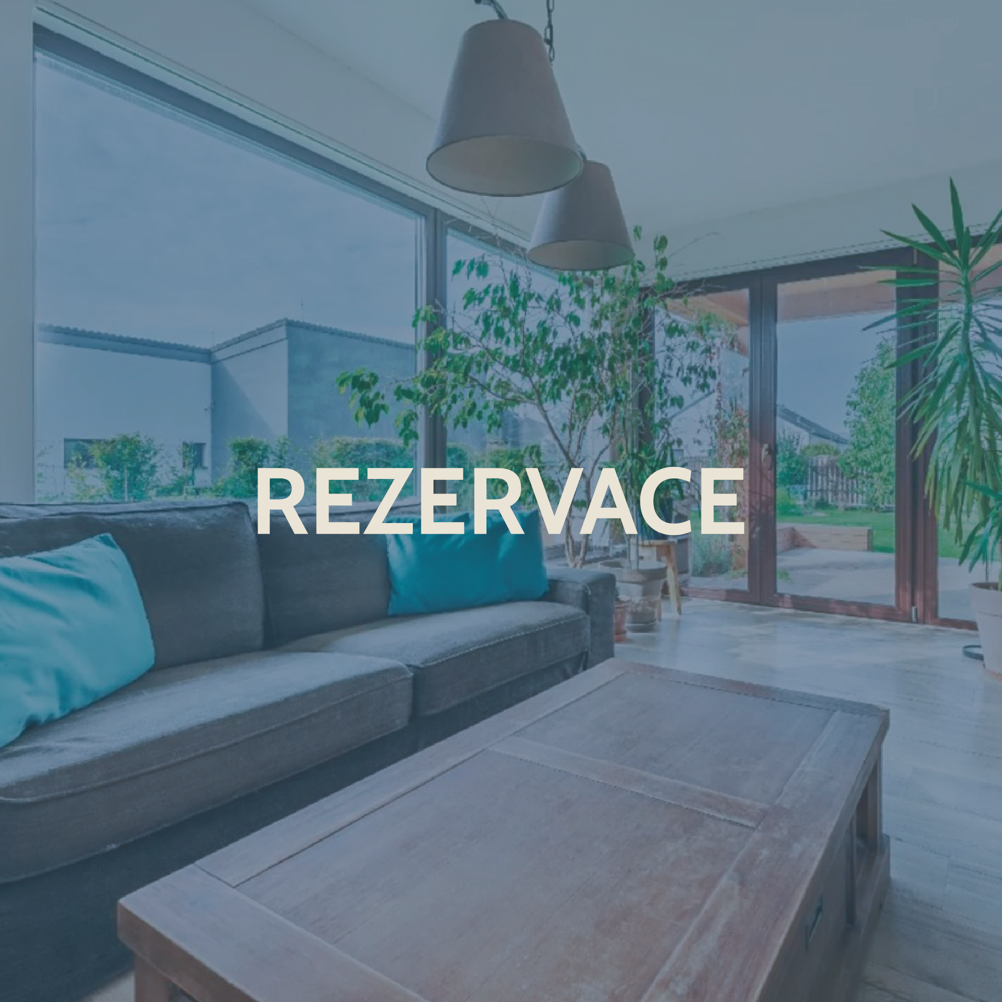 Modern living room with large windows, sofa with blue pillows, indoor plants, and a wooden coffee table, with open view to a garden outside.