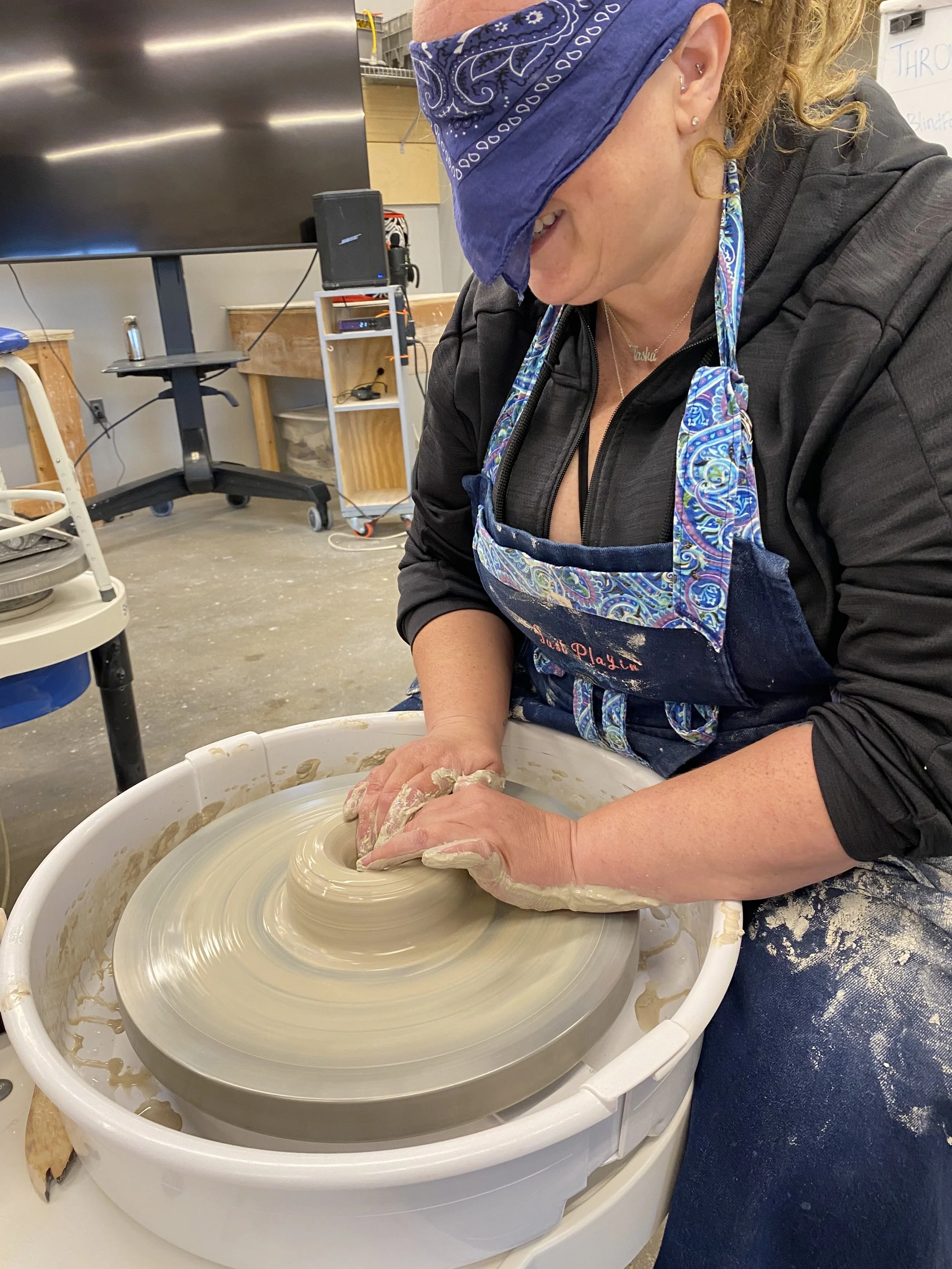 Tasha June wearing blue blindfold throwing ceramic pot with white b-mix clay
