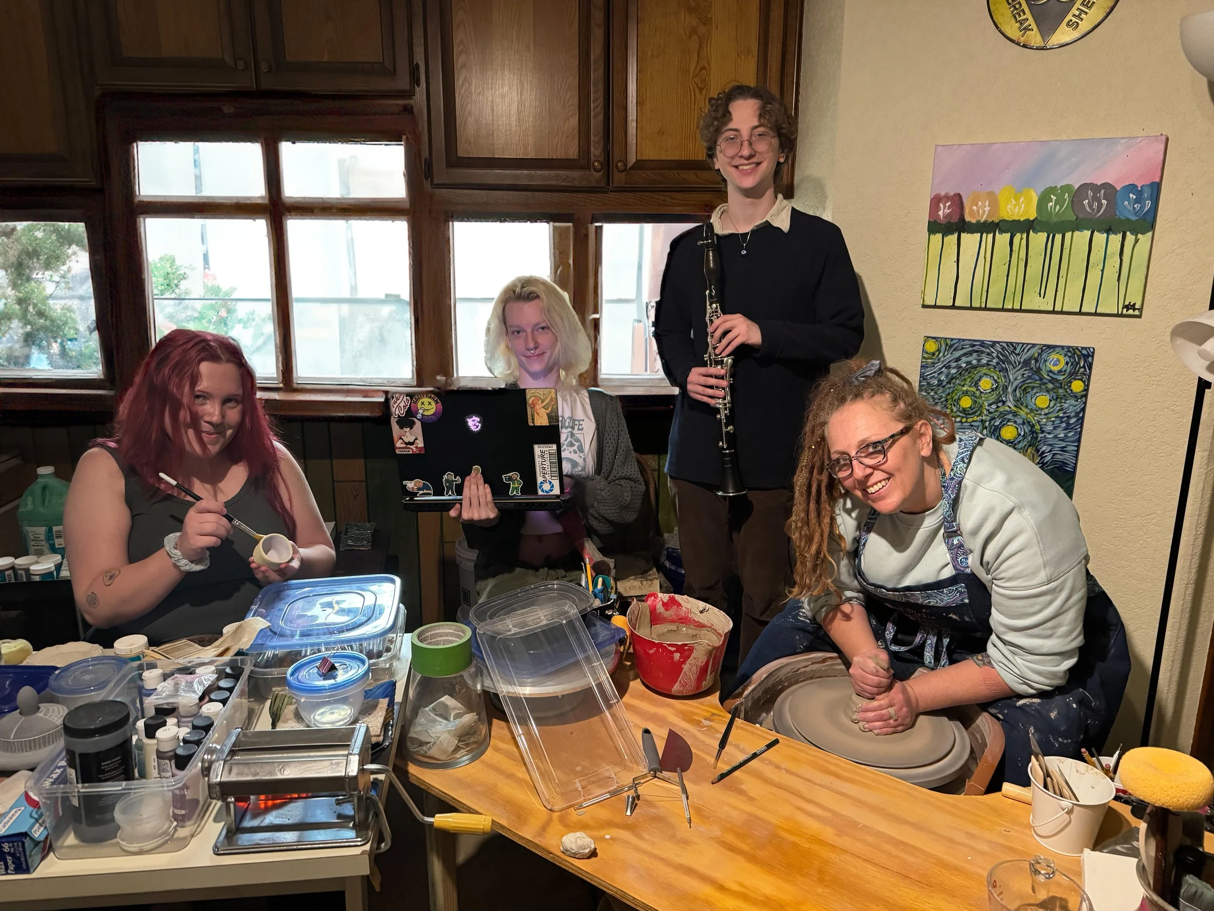 Vanna is painting a shot glass, Maeve is working on her computer, Kenidy has his clarinet out, and I am throwing a bowl on the wheel in the Tasha June Art Studio, sorry it is a mess, we are consistently working.