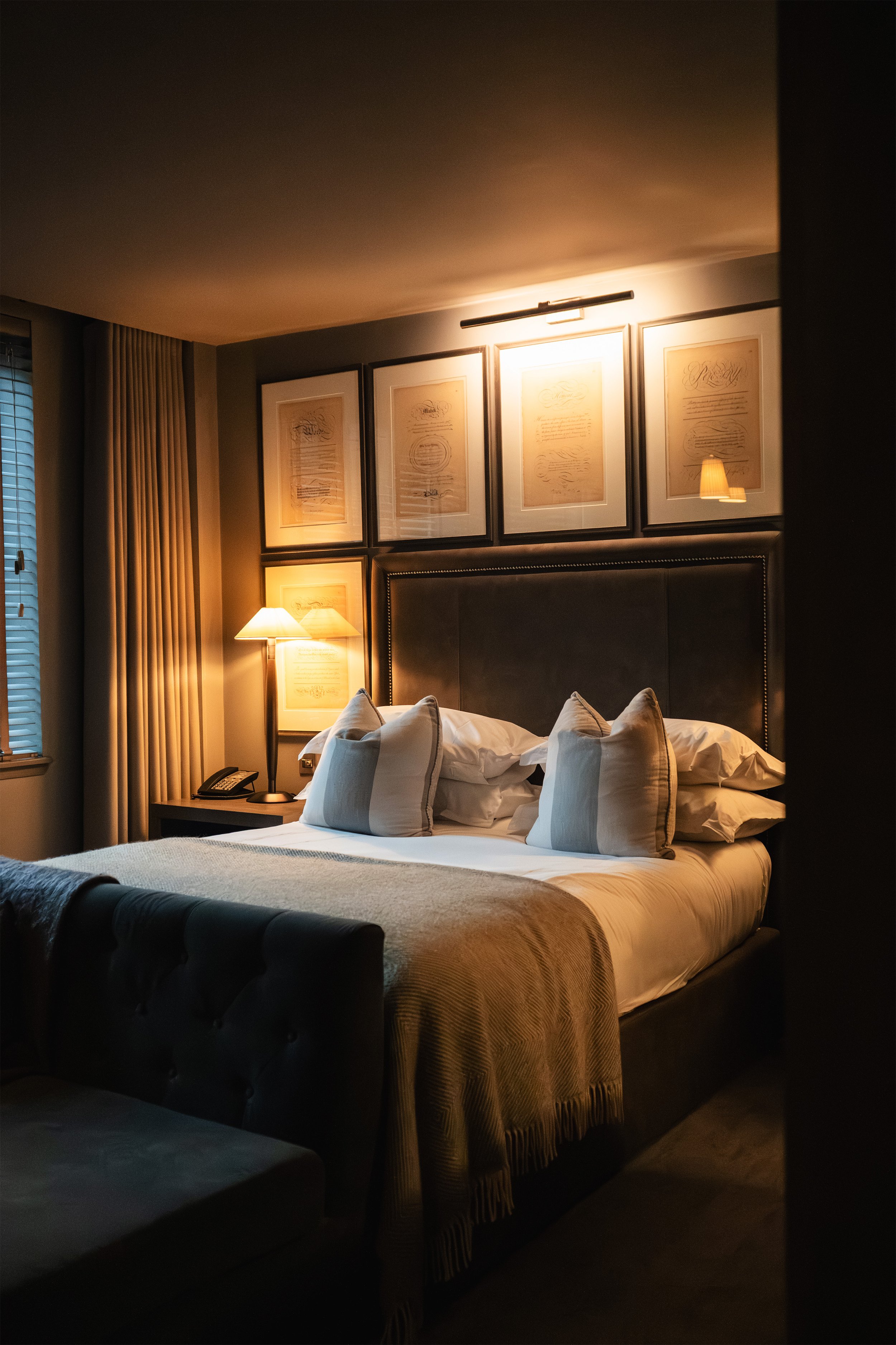 A cosy hotel bedroom in Glasgow with a neatly made bed, illuminated by warm lighting.