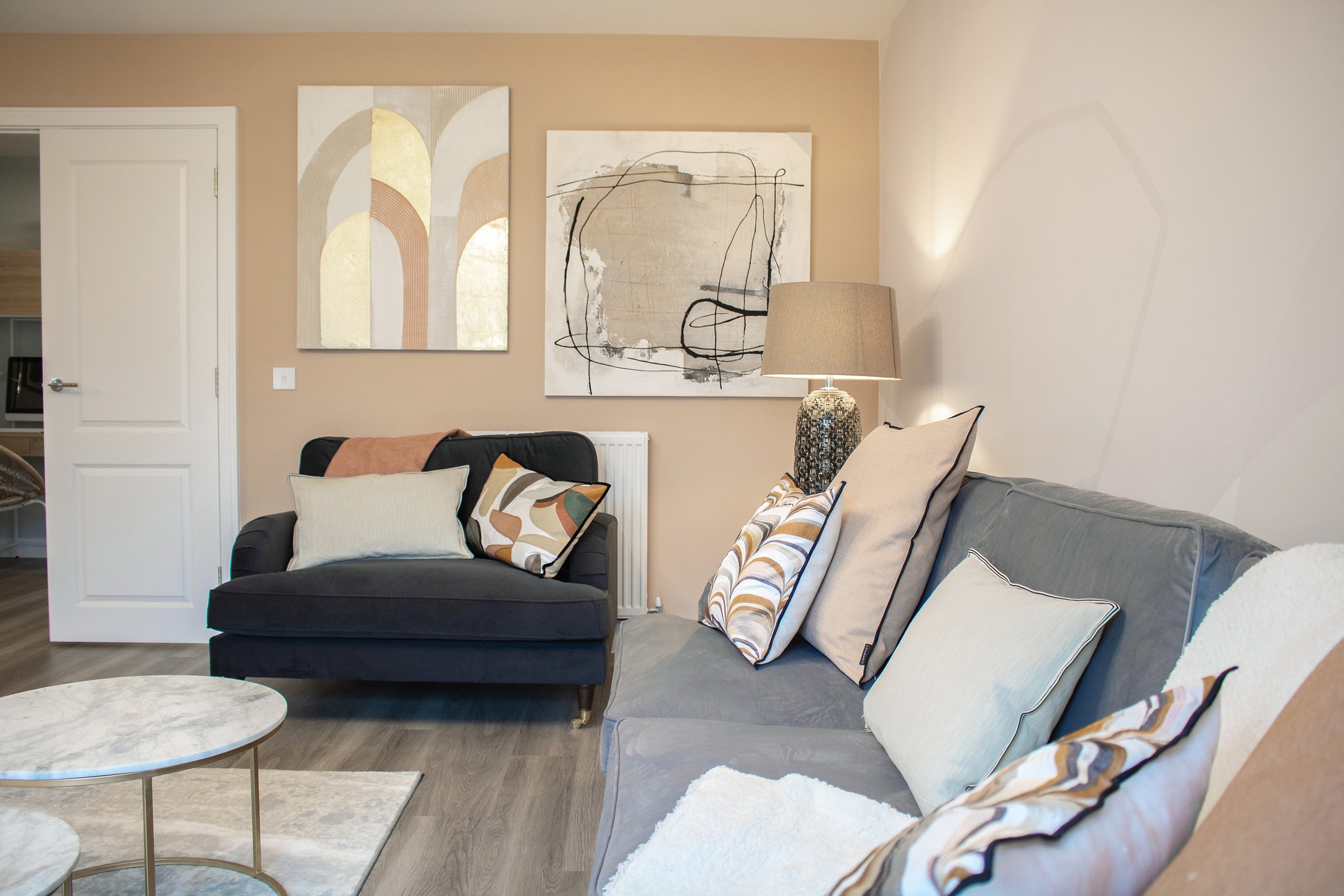 Living room with two sofas, pillows, a table, and wall art.
