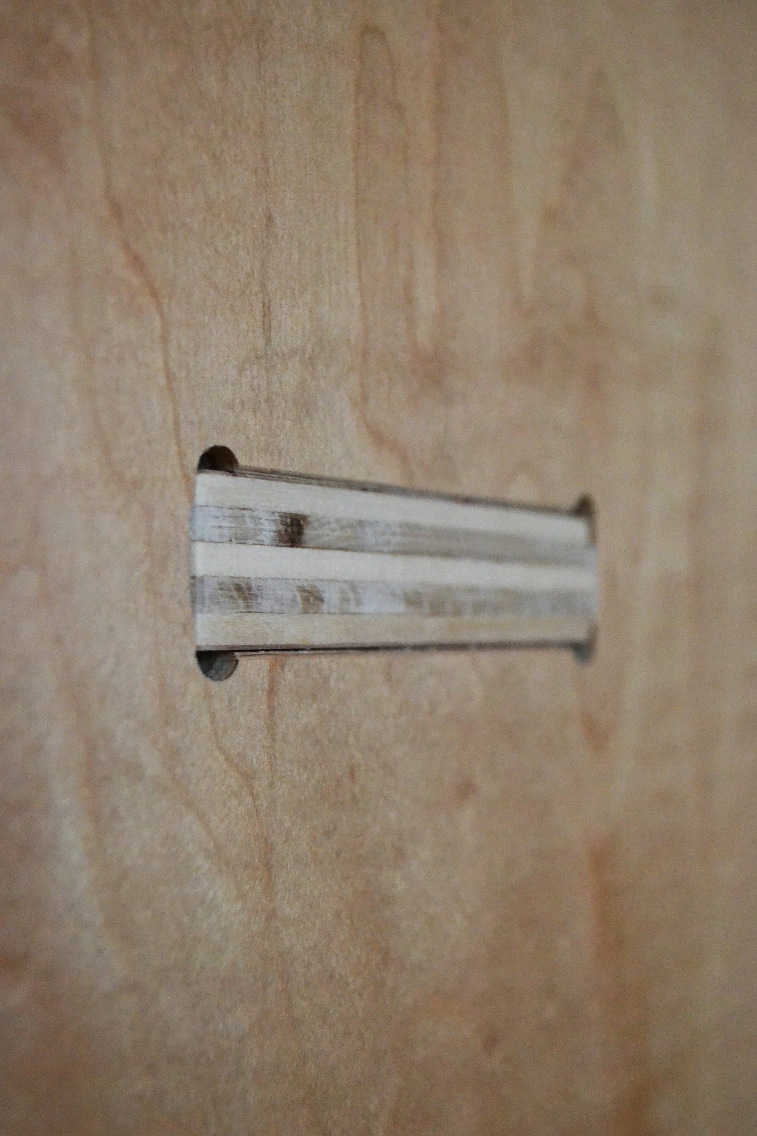Close-up of a rectangular metal slot in a wooden surface.