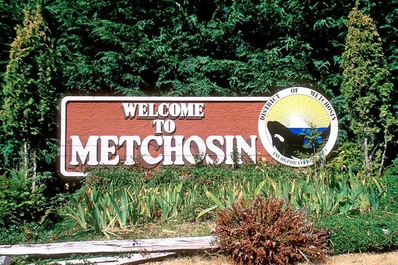Welcome to Metchosin British Columbia, Canada.  sign with trees and plants in the background.