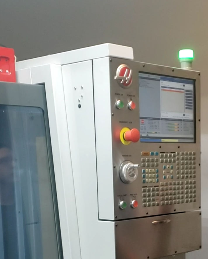 Industrial machine control panel with a screen, warning lights, and various buttons and knobs.