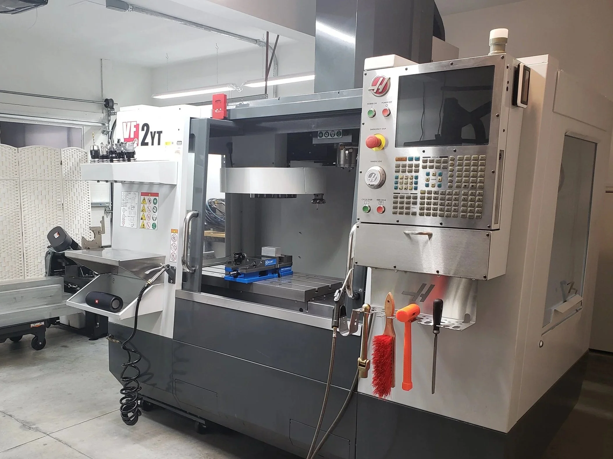 Computer numerical control (CNC) milling machine used for manufacturing and machining processes, with various tools and controls attached.