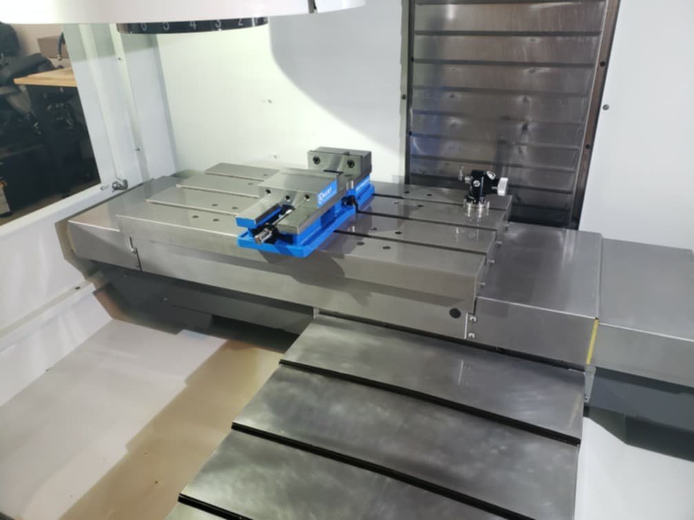 A large industrial milling machine with a metallic surface, adjustable components, and a worktable, situated in a workshop or manufacturing setting.