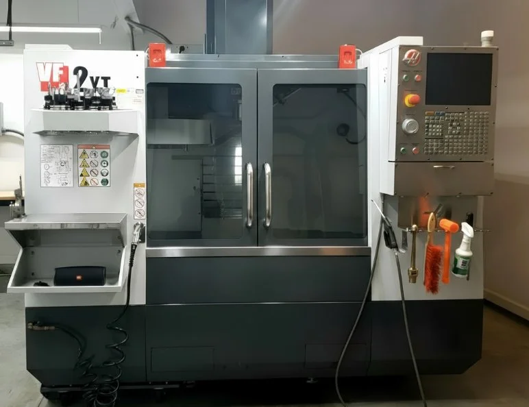 Computerized CNC machine with control panel and safety guard.