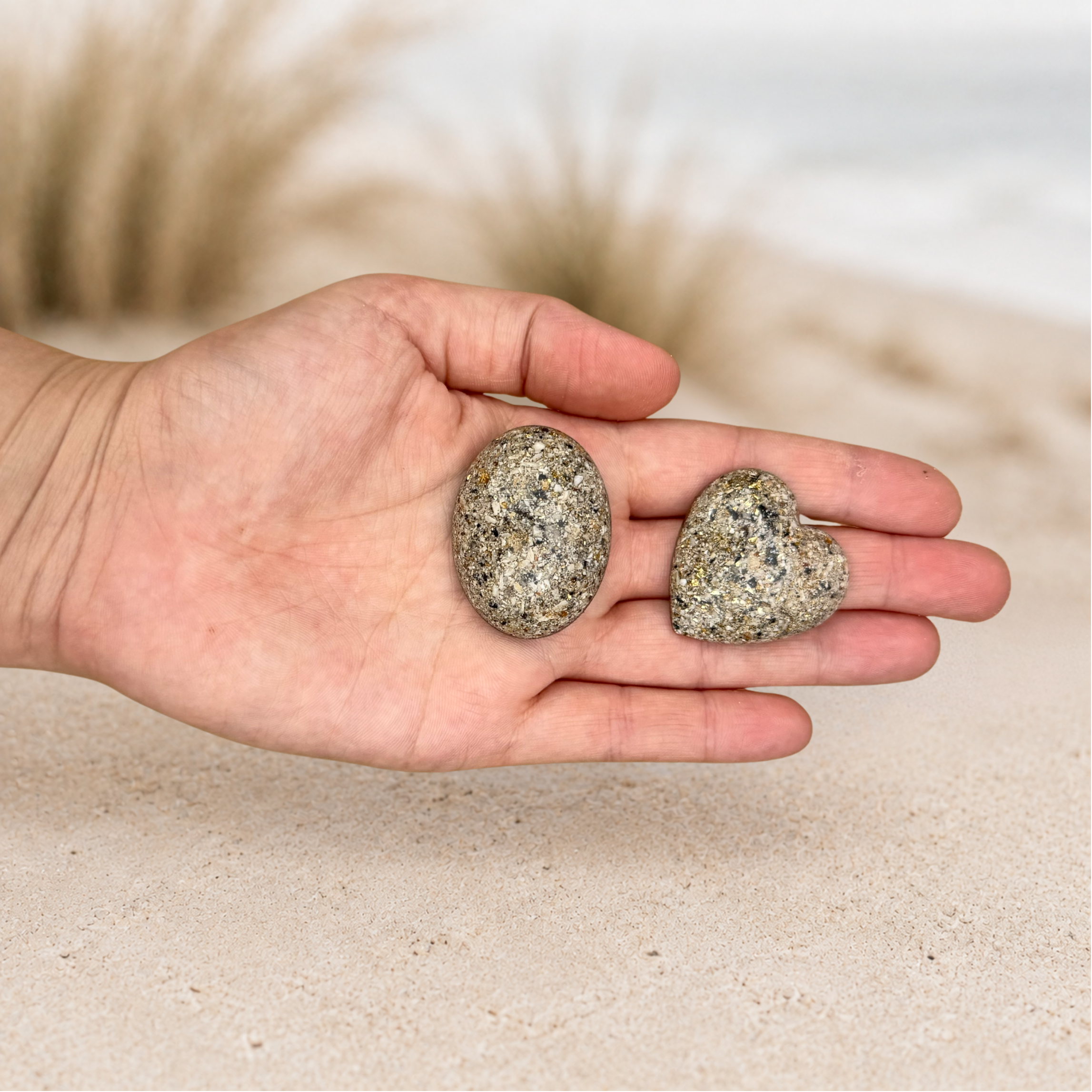 Small heart and oval memorial holding stones resting in a hand, showing their smooth finish and comforting palm-sized scale. (2).png
