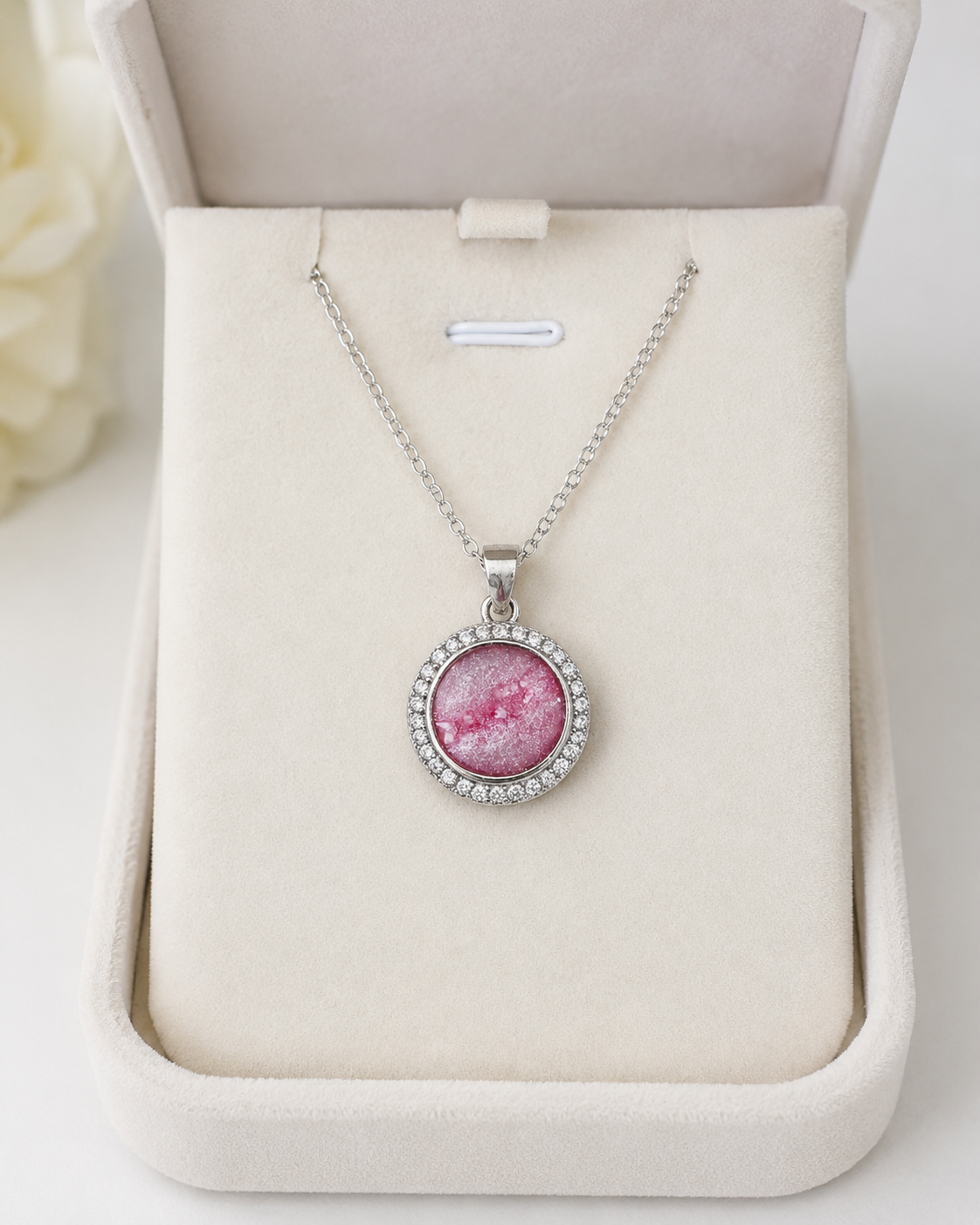 Pink resin pet memorial pendant with ashes in a silver halo setting