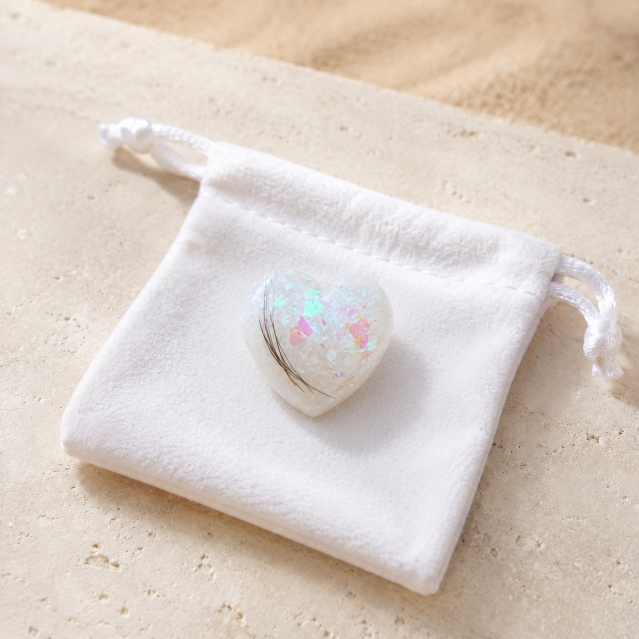 Heart-shaped resin memorial holding stone handmade with a pet’s hair and opalescent flakes, displayed on a white velvet keepsake pouch..png