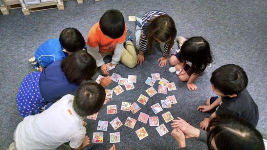 Children playing a matching game with picture cards on the carpet