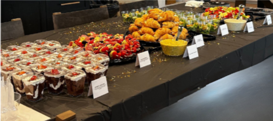 A buffet table with various desserts, fruits, and dips set up for an event.