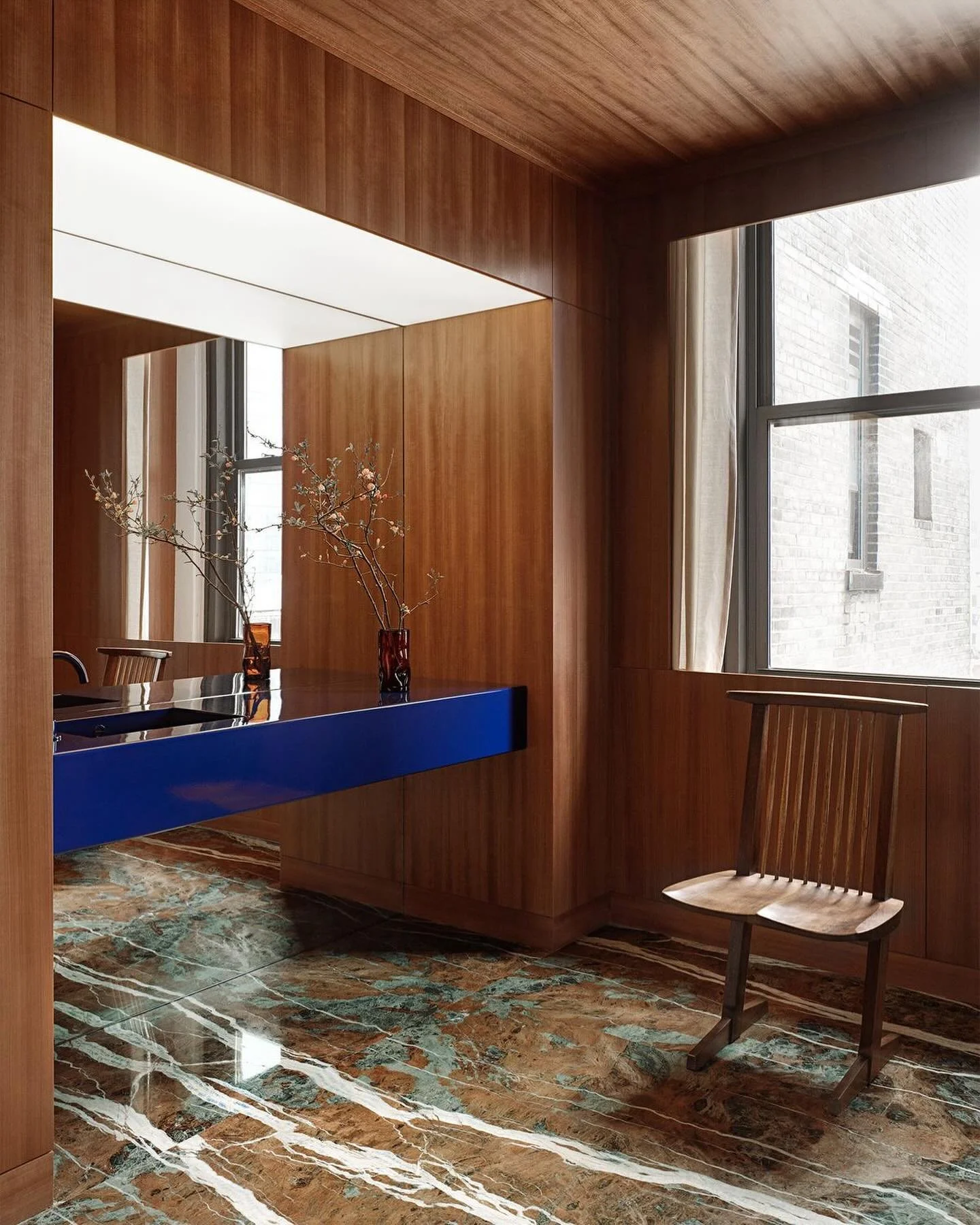 This minimalist bathroom combines light-toned stone surfaces and sleek black fixtures, highlighted by a striking cobalt blue sink. The design balances elegance with a bold, modern touch.

@halleroed