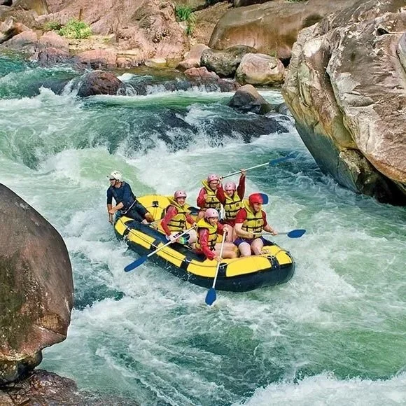 Group of people white-water rafting on a river surrounded by large rocks and greenery.