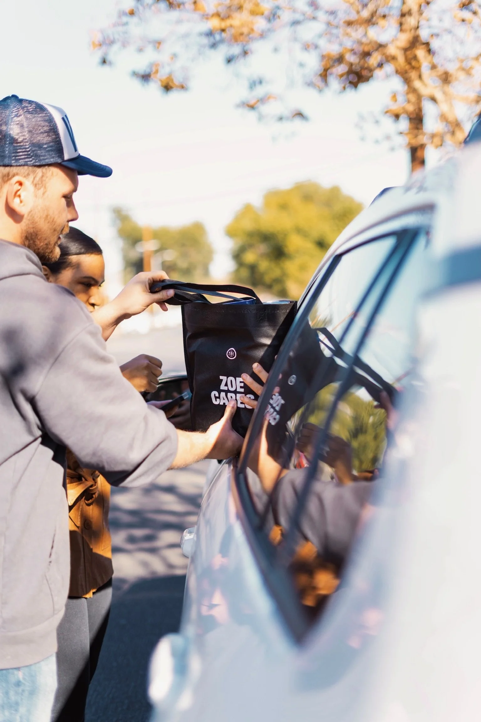 ZOE Cares volunteers handing a meal bag to a family in their car