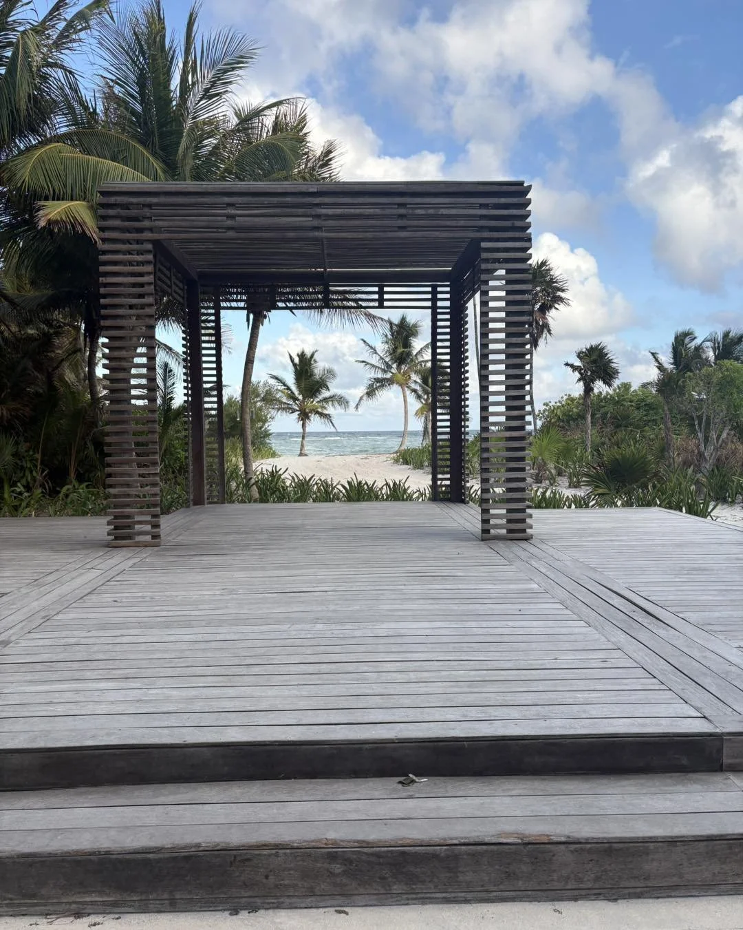 Luxury beach resort with wooden deck overlooking ocean and palm trees, ideal for tropical vacations, destination weddings, and romantic getaways.