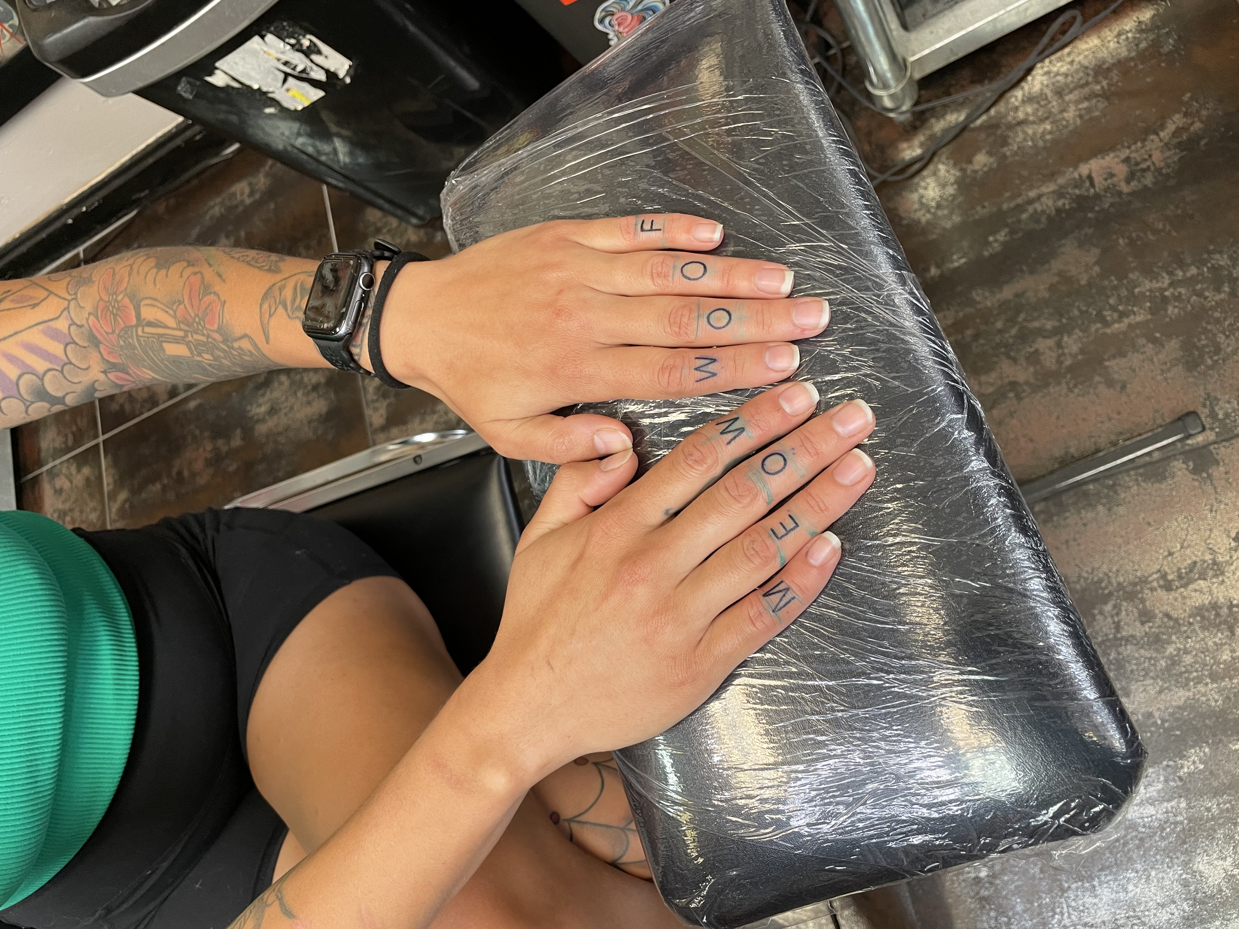 Humorous fine line finger tattoo set reading "MEOW" across one hand and "WOOF" across the other in bold block letters, a playful tribute to cats and dogs, custom tattoo by Nick at Big Kahuna Tattoo in Boca Raton, FL.