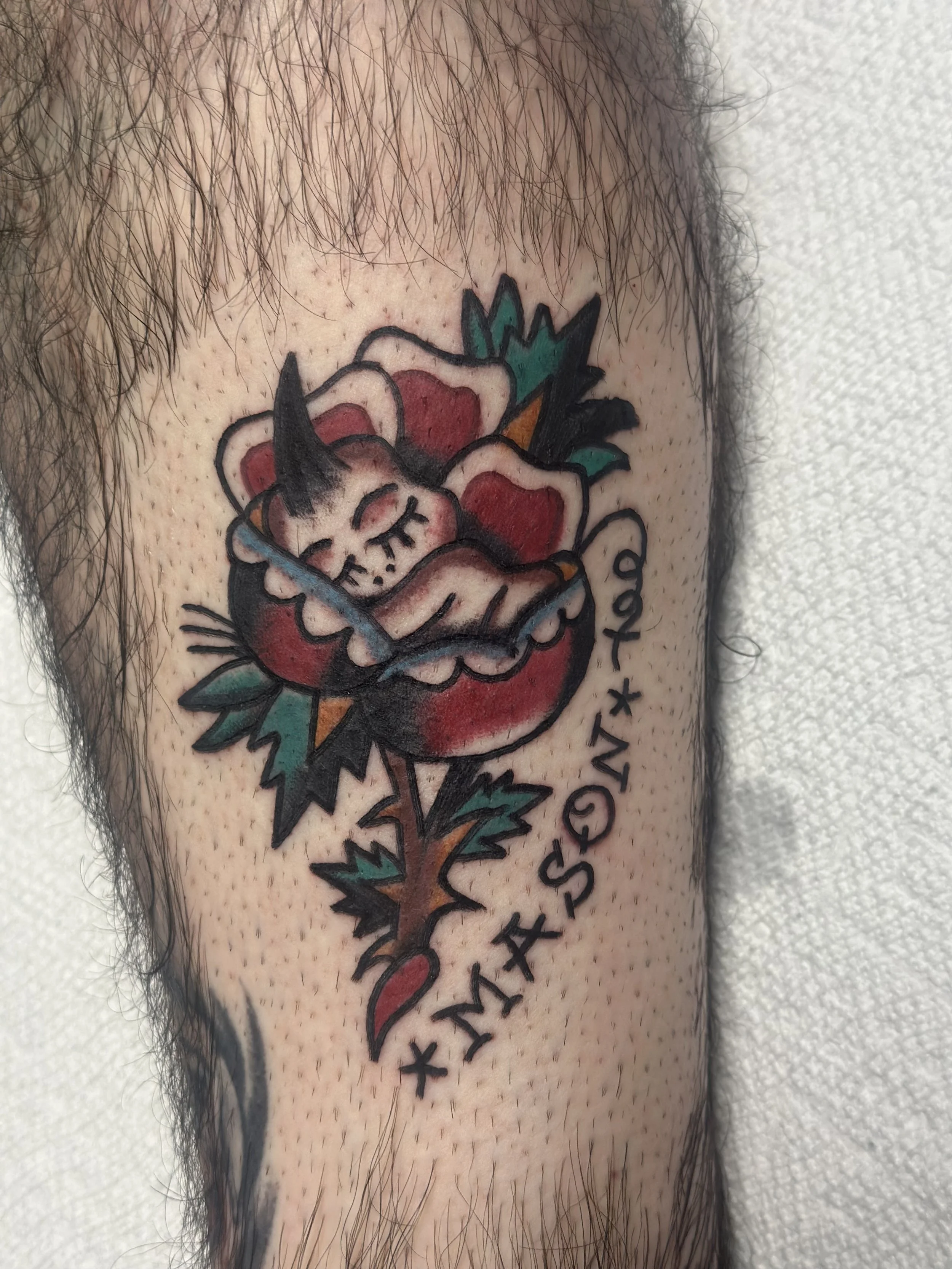 Traditional American color forearm tattoo featuring a sleeping baby nestled inside a bold red rose with green leaves, gold thorns, and a banner reading "Mason," custom tattoo by Dan at Big Kahuna Tattoo in Boca Raton, FL.