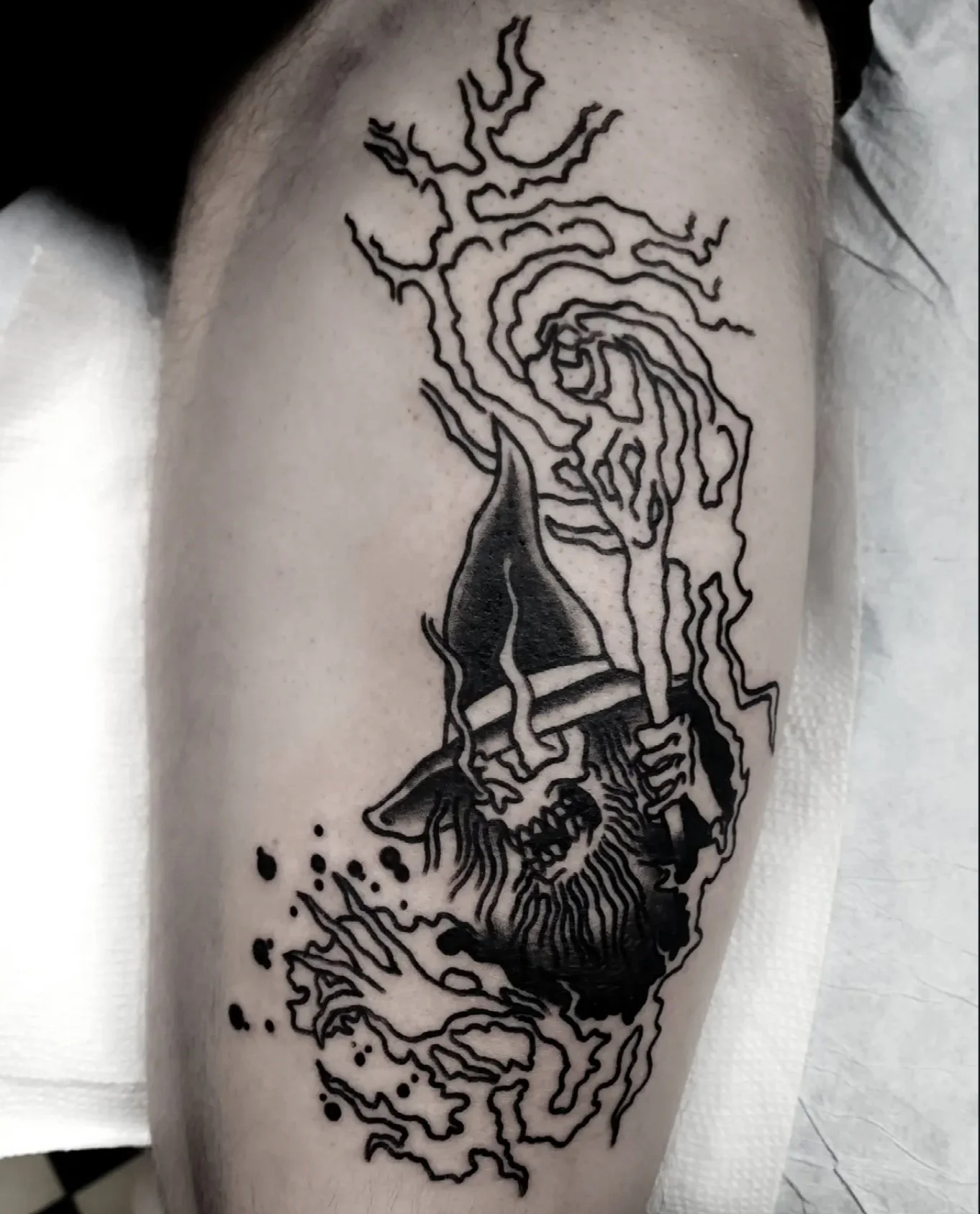 Bold black and grey traditional leg tattoo featuring a skull wizard with a pointed hat wielding a staff with lightning energy crackling from the top, custom tattoo by Brandon Perez at Big Kahuna Tattoo in Boca Raton, FL