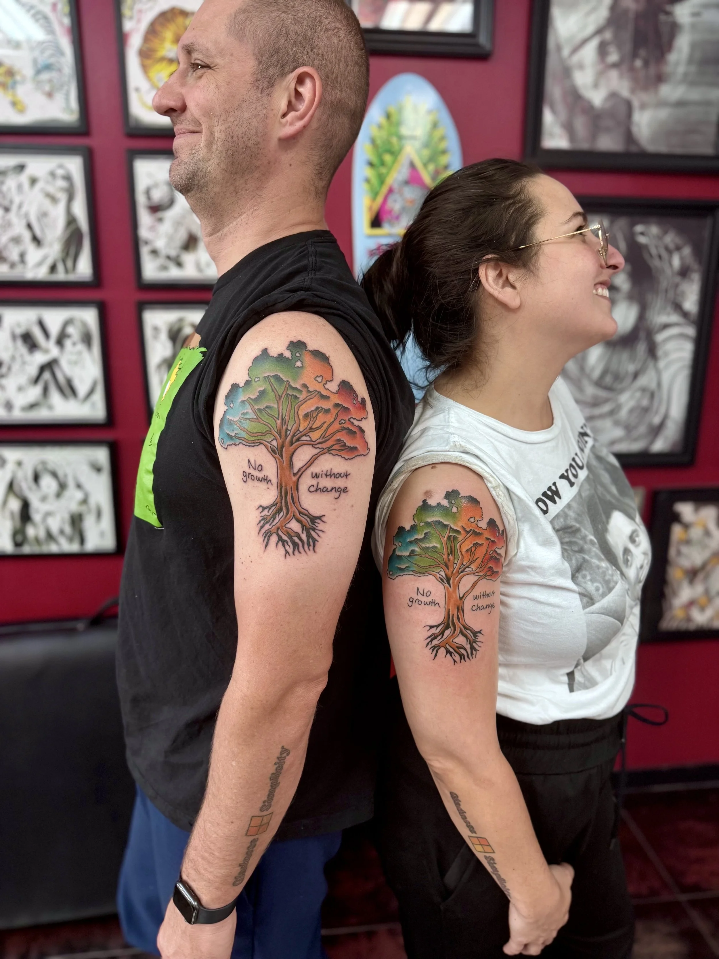 Matching color shoulder tattoos for two, featuring a vibrant tree of life with a multicolored canopy of teal, orange, and green foliage above deeply rooted exposed roots, inscribed with the words "No growth without change," custom matching tattoos by