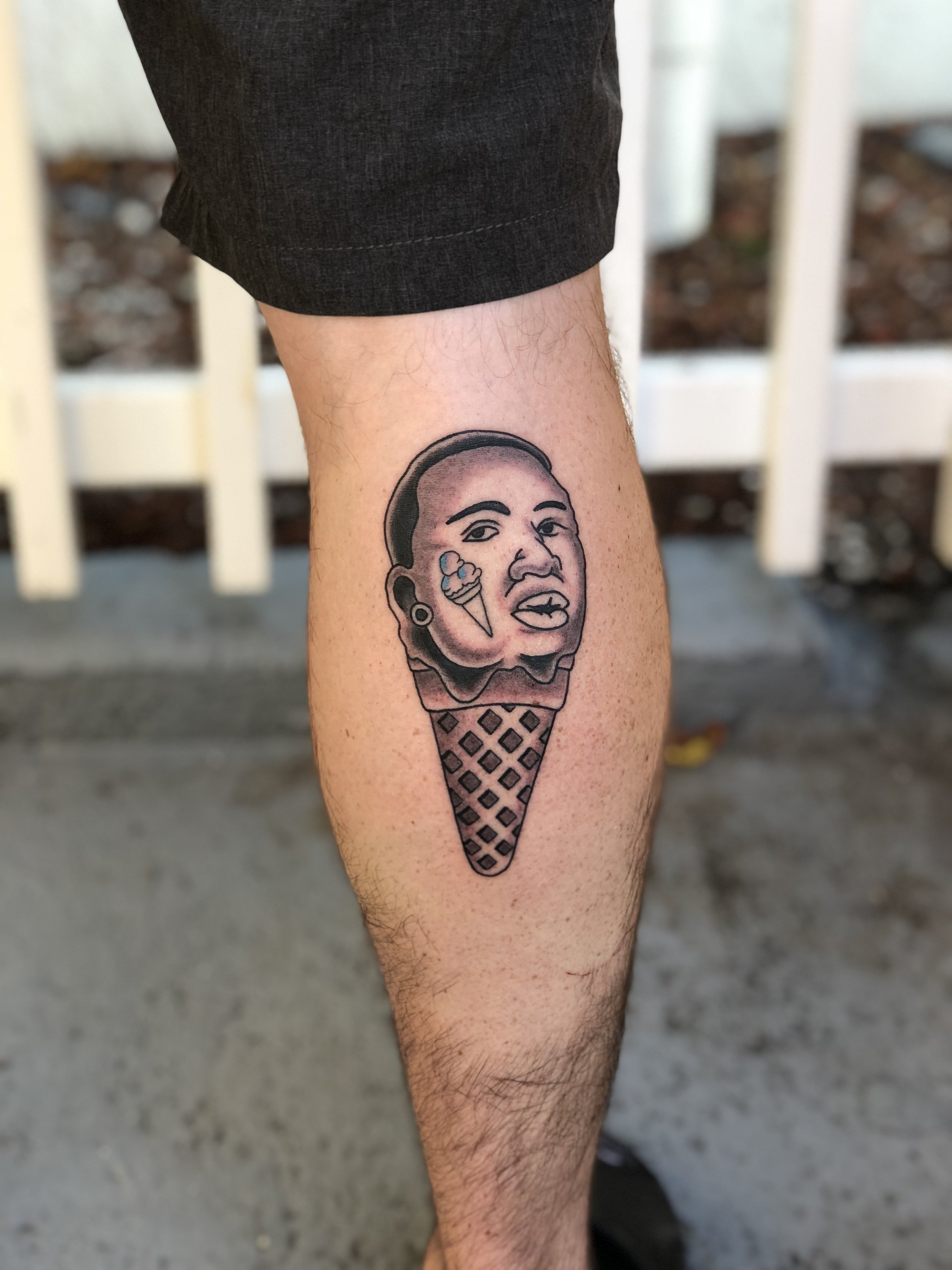 Humorous and creative black and grey calf tattoo featuring a portrait of Gucci Mane as the scoop of a detailed waffle cone ice cream, custom tattoo by Nick at Big Kahuna Tattoo in Boca Raton, FL.