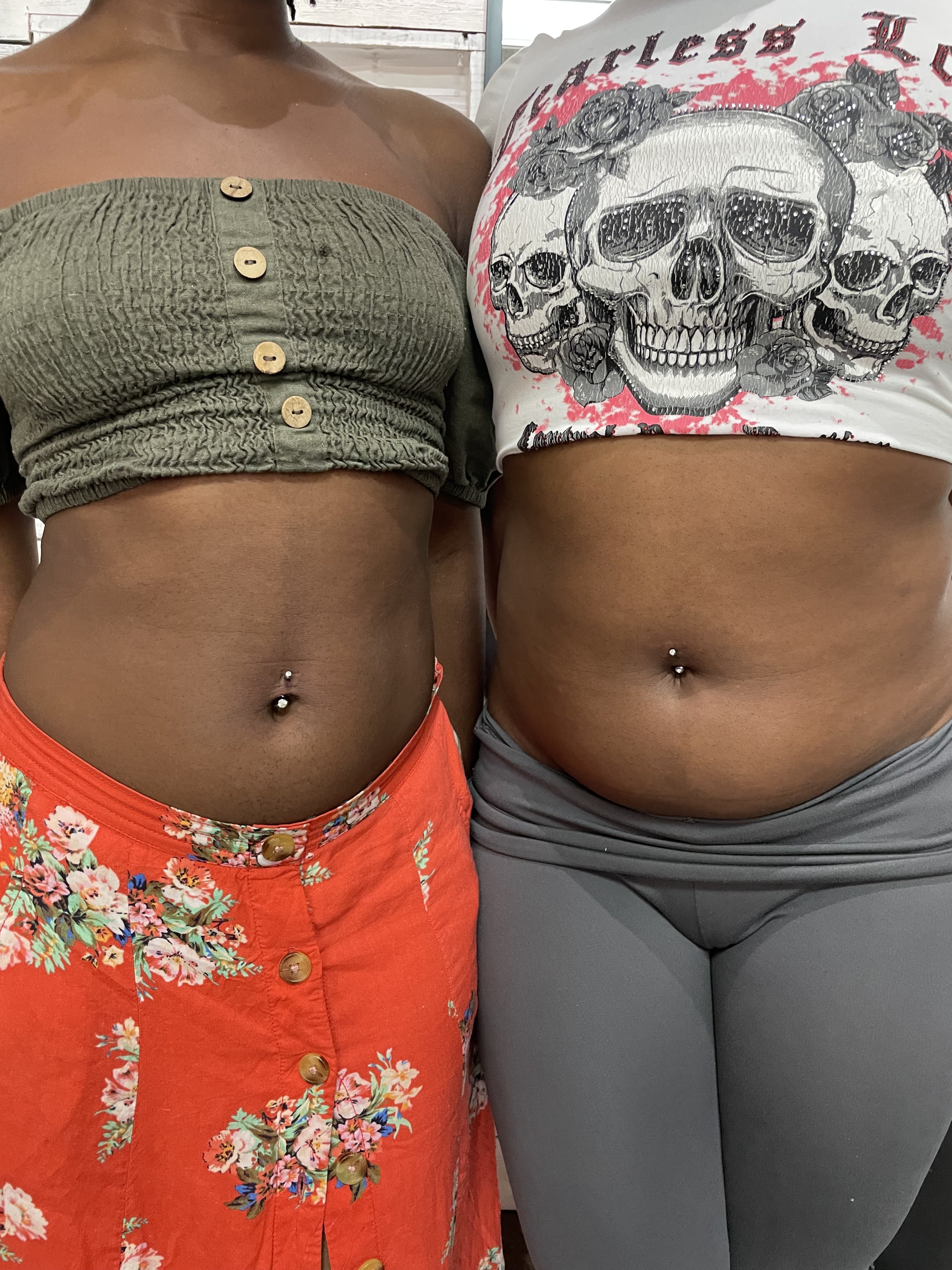 Close-up of matching navel piercings on two clients. Both fitted with curved barbells and gem-set tops. Clean placement, fresh piercings done same day. By Nick at Big Kahuna Tattoo in Boca Raton.