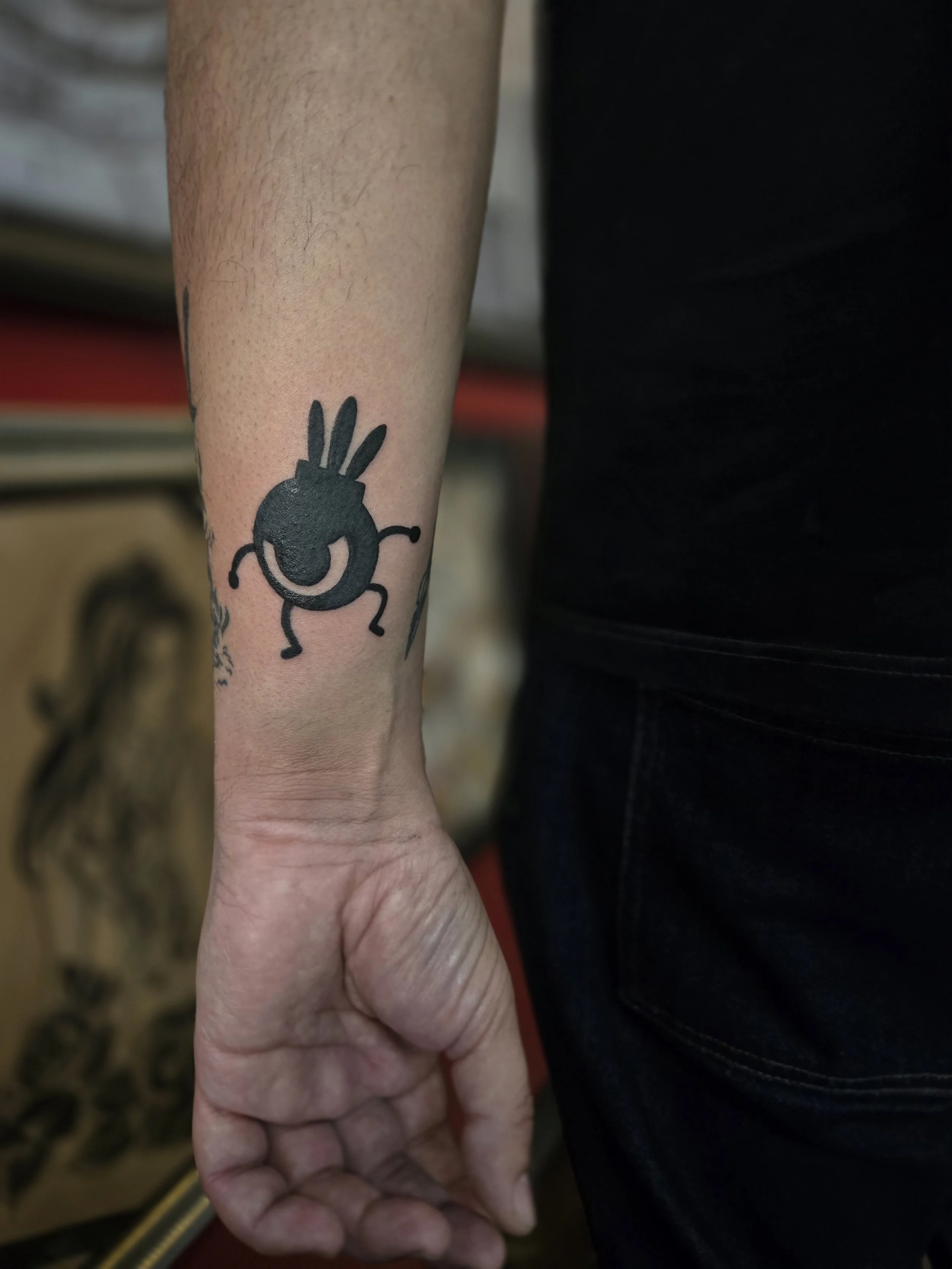 Bold black traditional wrist tattoo featuring a Patapon character from the PlayStation video game Patapon, custom gaming tribute tattoo by Brandon Perez at Big Kahuna Tattoo in Boca Raton, FL
