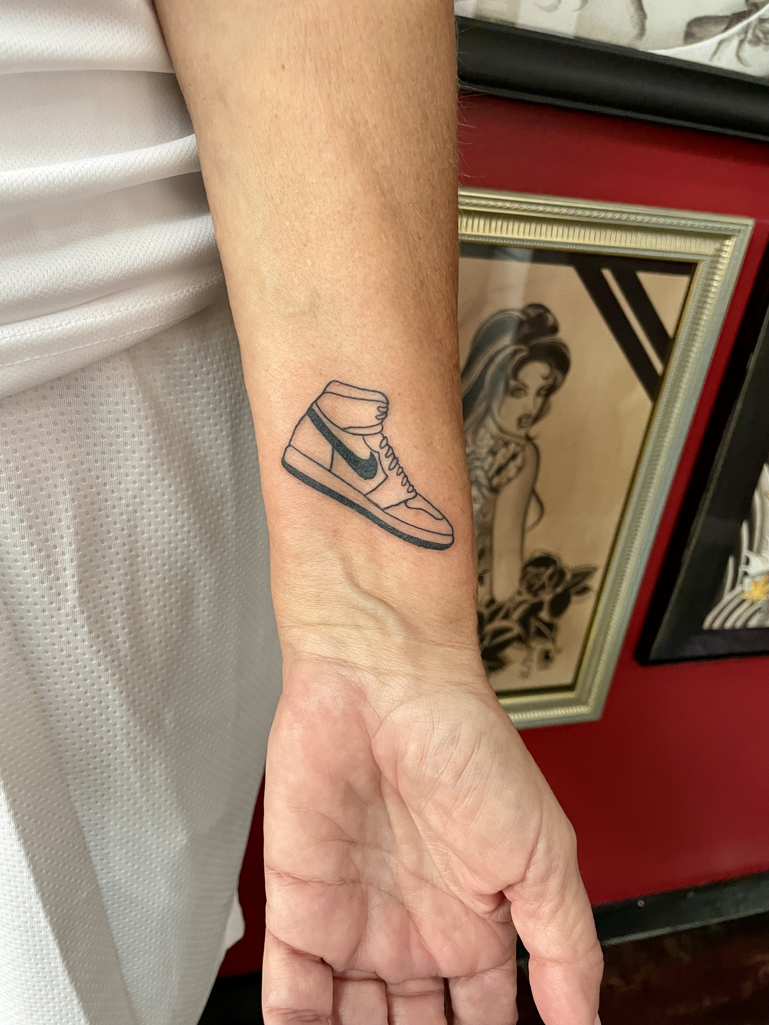 Fine line wrist tattoo featuring a minimalist Air Jordan 1 sneaker design with bold black linework, custom tattoo by Nick at Big Kahuna Tattoo in Boca Raton, FL.