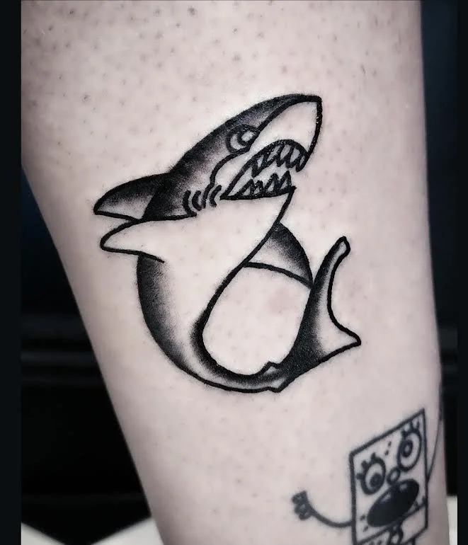 Bold black and grey traditional leg tattoo featuring a great white shark with open jaws and bold linework, custom tattoo by Brandon Perez at Big Kahuna Tattoo in Boca Raton, FL