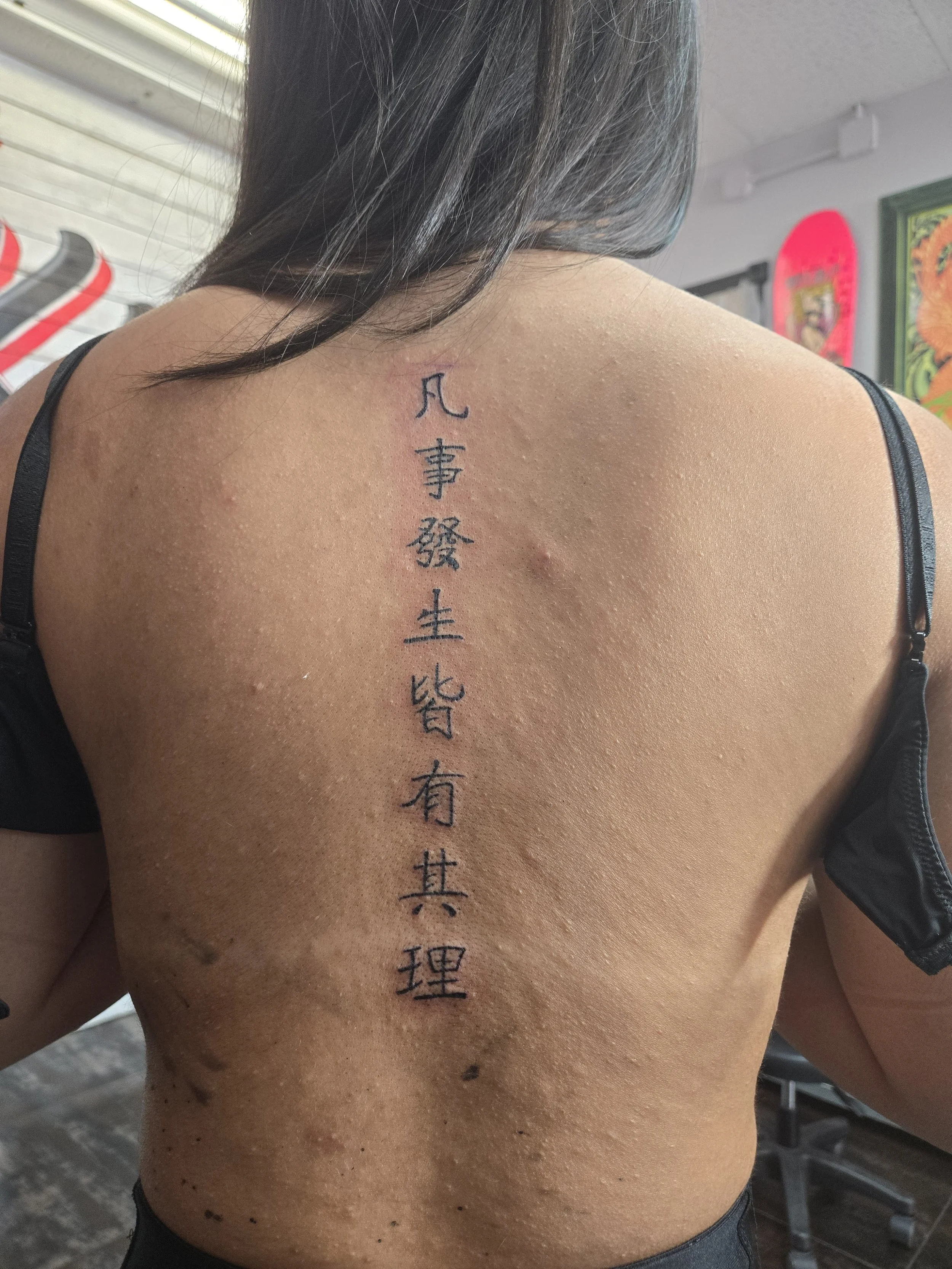 Bold black script spine tattoo featuring Chinese characters running vertically down the back, custom lettering tattoo by Brandon Perez at Big Kahuna Tattoo in Boca Raton, FL