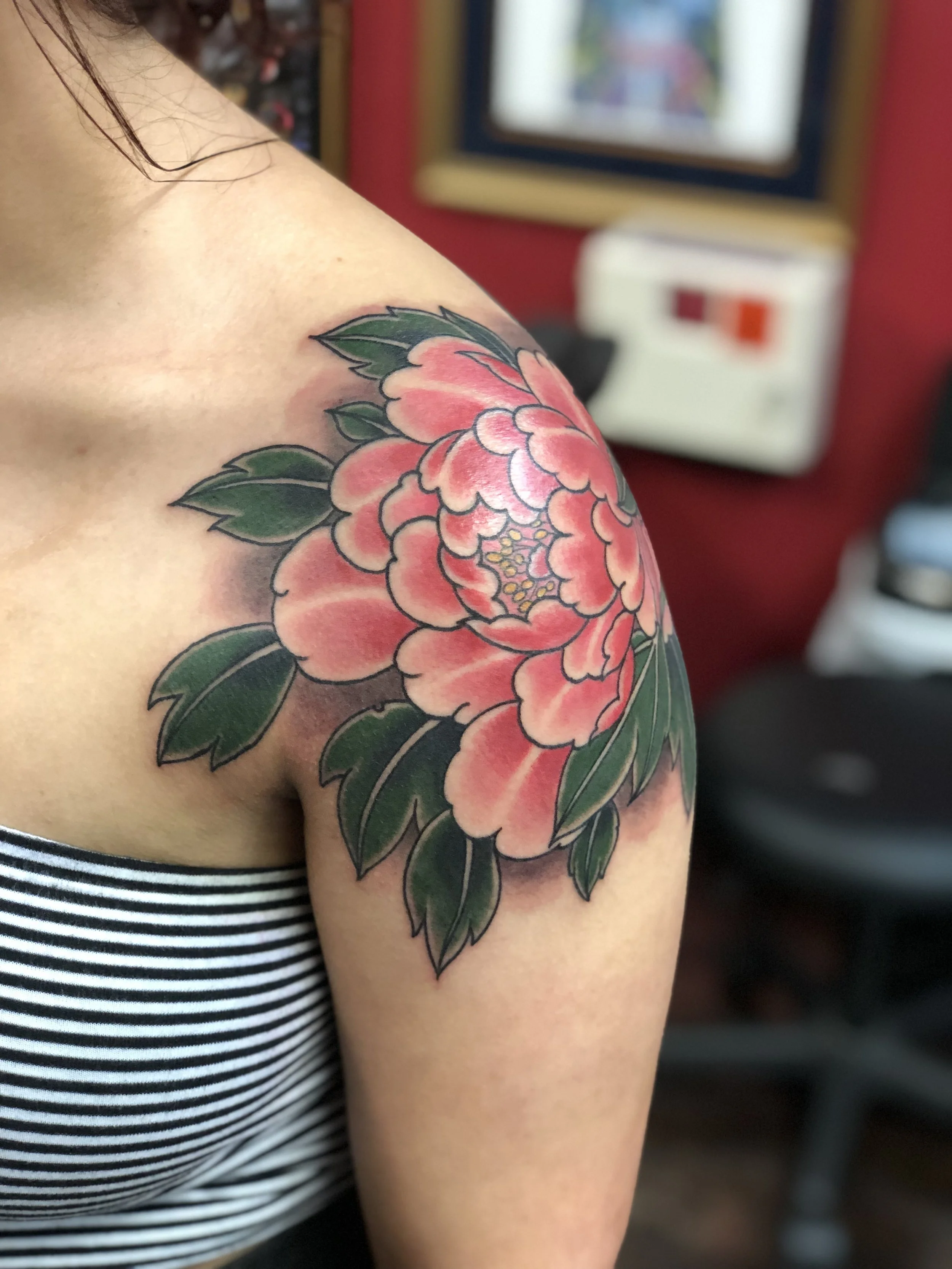 Japanese style color tattoo featuring a large pink peony with rich green leaves covering the shoulder cap, custom tattoo by Nick at Big Kahuna Tattoo in Boca Raton, FL.