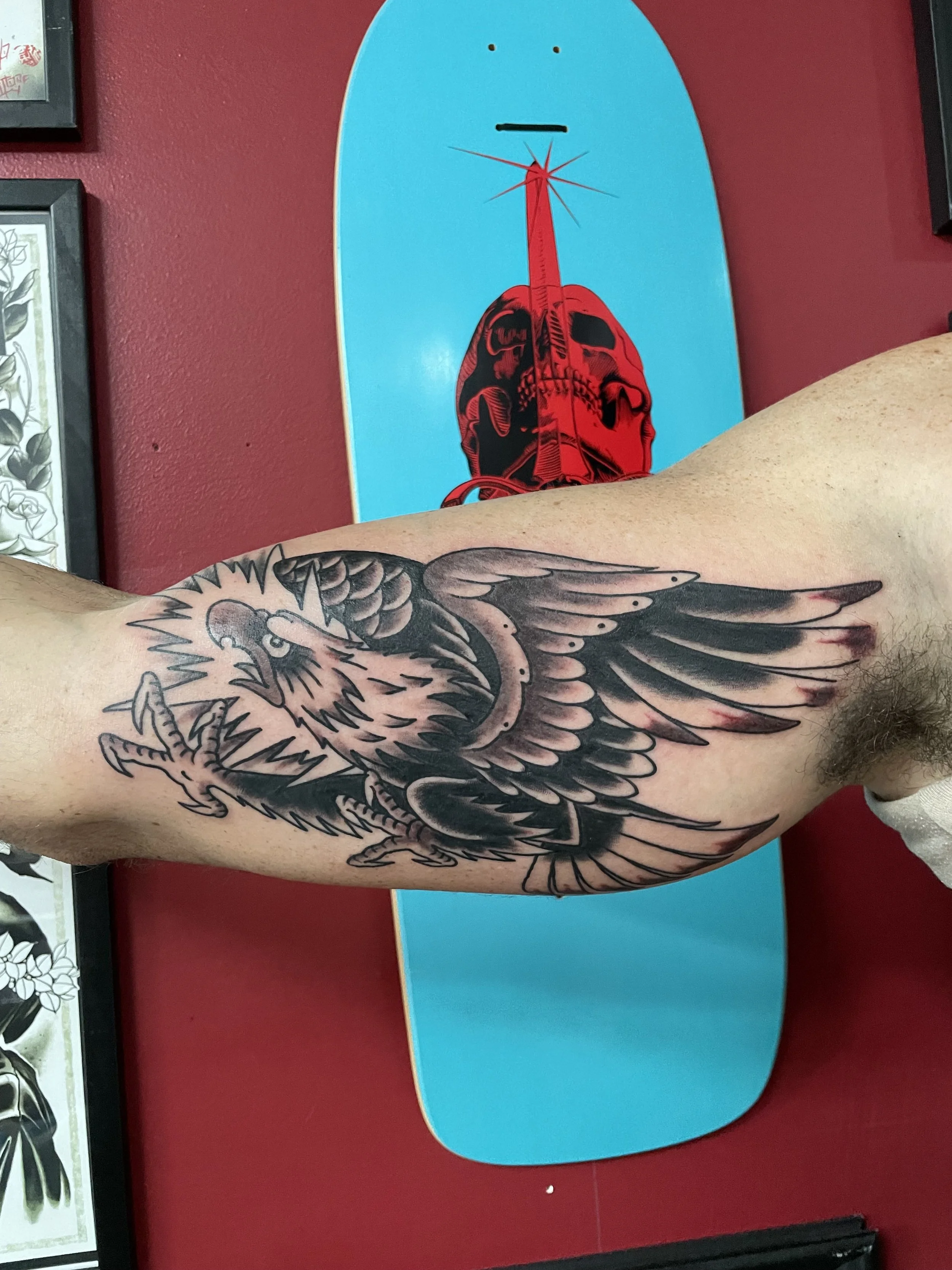 Wings fully spread and talons forward. This black and grey eagle on the forearm is all aggression and movement, the kind of piece that looks like it could take flight right off the arm. Traditional American forearm tattoo by Nick at Big Kahuna Tattoo
