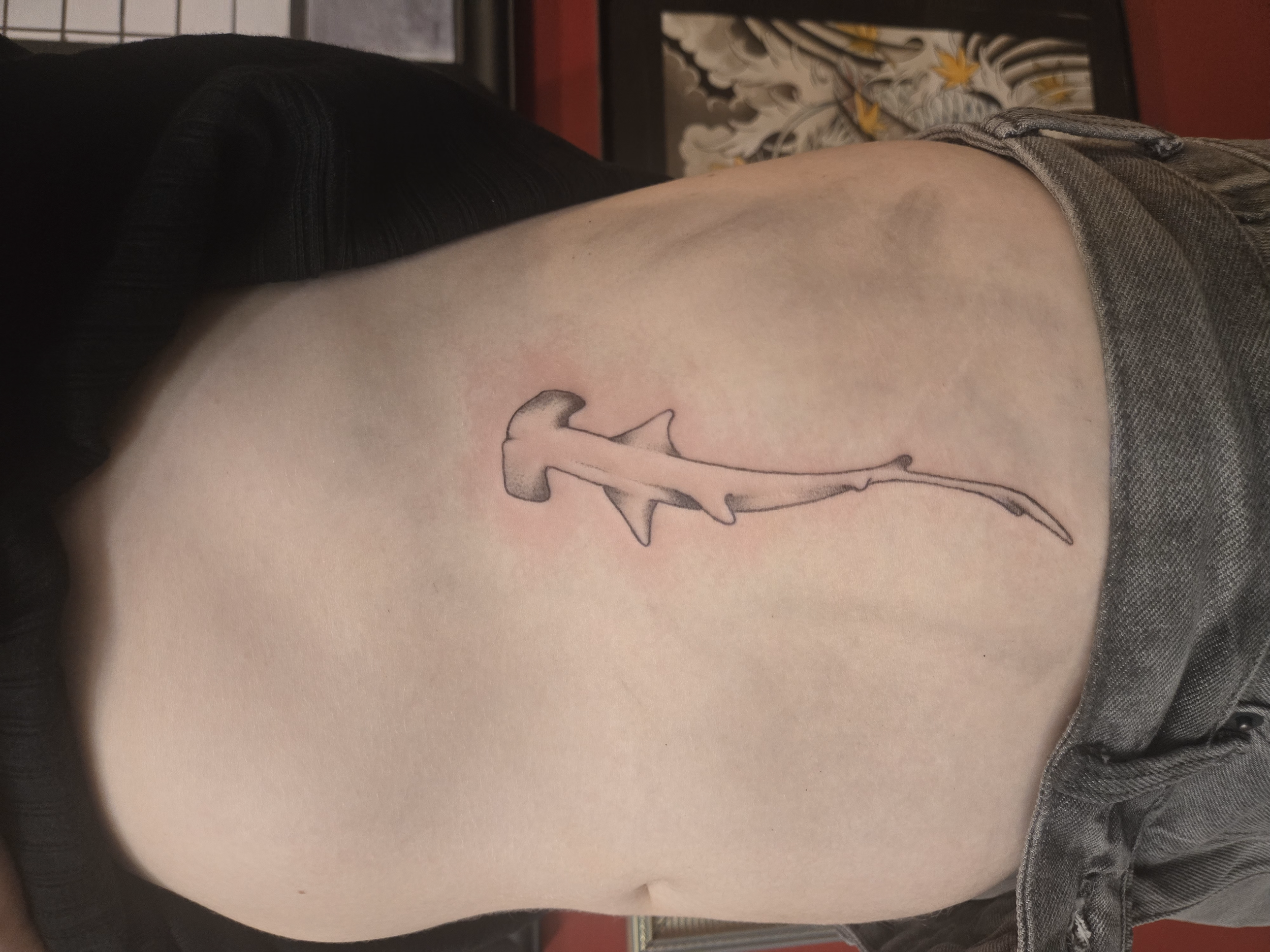 Fine line rib tattoo featuring a minimalist hammerhead shark in a vertical orientation with soft shading, custom tattoo by Brandon Perez at Big Kahuna Tattoo in Boca Raton, FL