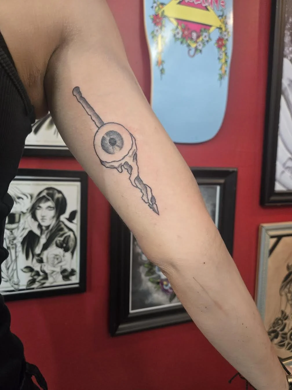 Black and grey traditional forearm tattoo featuring a surreal eyeball skewered on a pointed pike, custom tattoo by Brandon Perez at Big Kahuna Tattoo in Boca Raton, FL