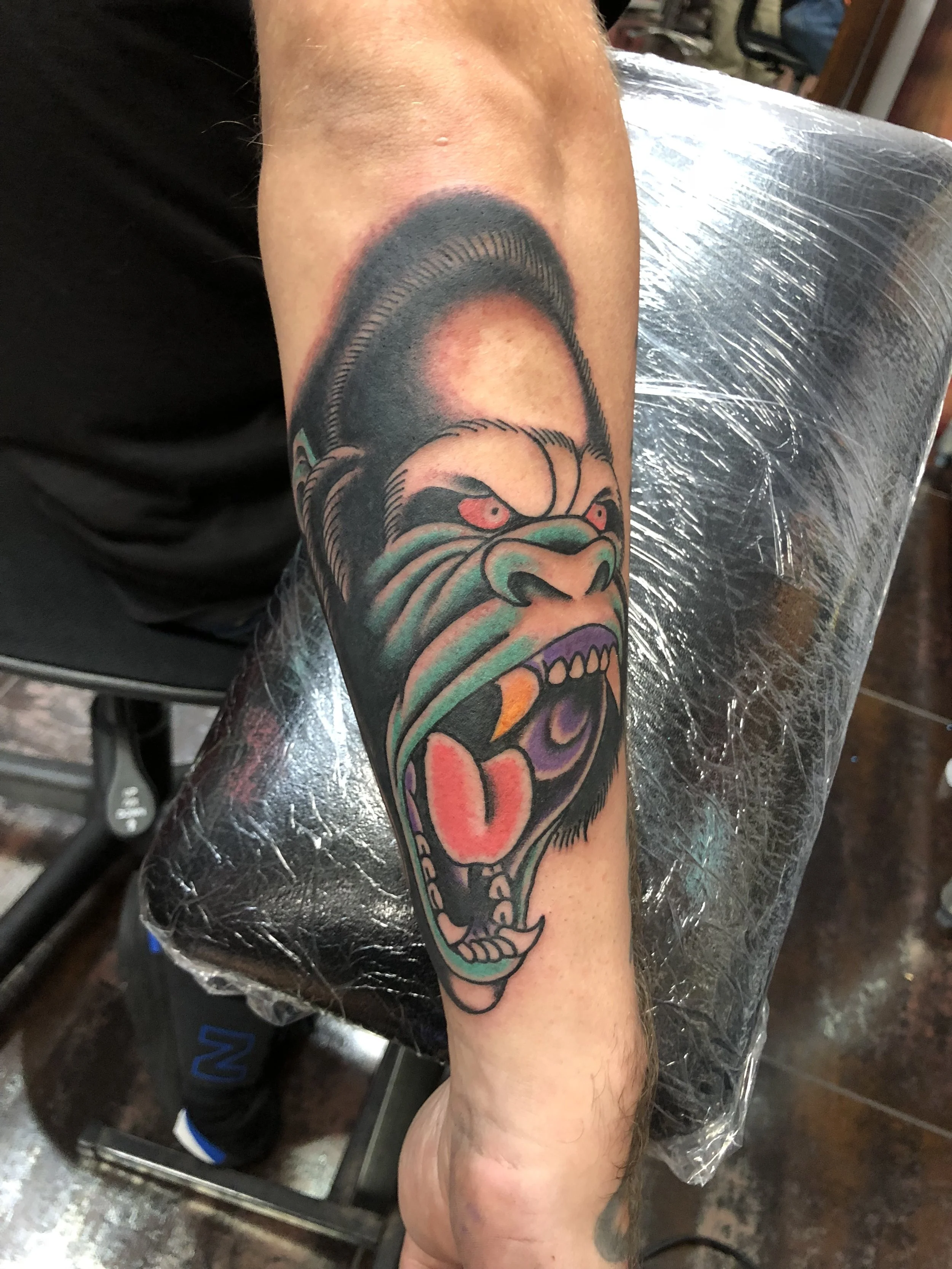 Traditional American color forearm tattoo featuring a snarling gorilla with bold linework and vibrant green, purple, and red tones, custom tattoo by Nick at Big Kahuna Tattoo in Boca Raton, FL.