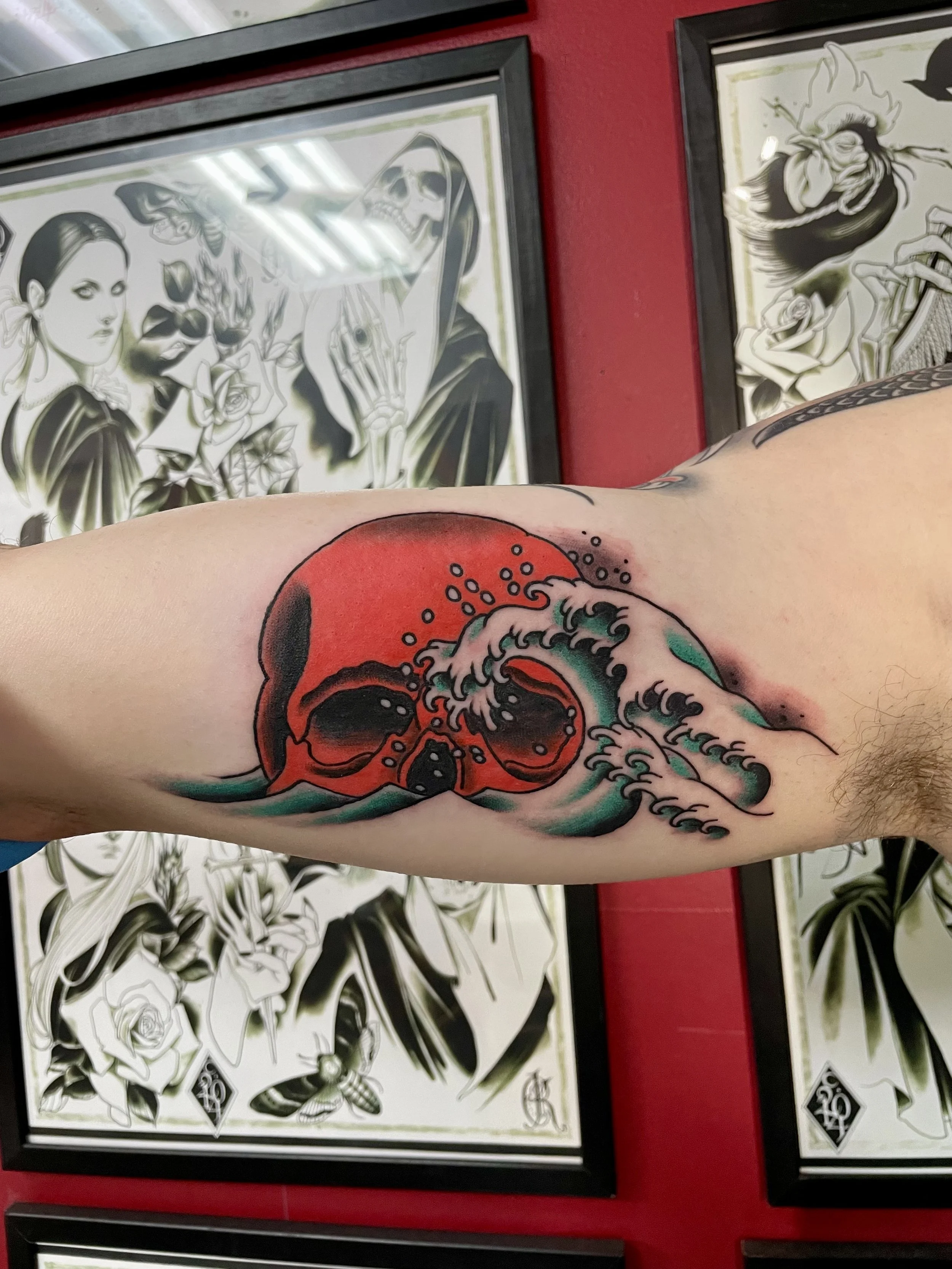 East meets West right on the inner bicep. A bold red skull half submerged in a crashing teal Japanese wave. Traditional American color elbow tattoo by Nick at Big Kahuna Tattoo in Boca Raton, FL.
