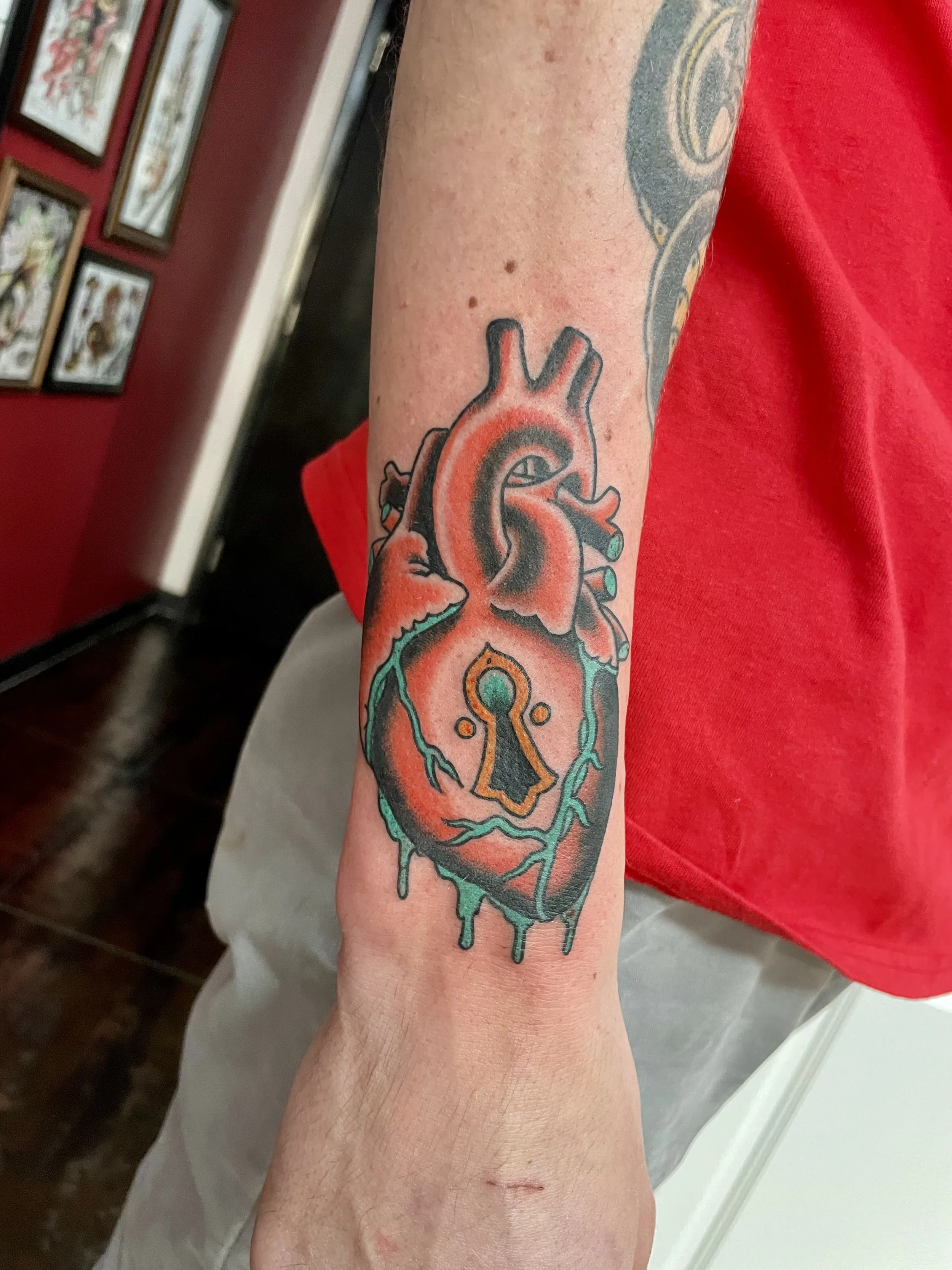 Color traditional forearm tattoo featuring a detailed anatomical heart with a gold keyhole, custom tattoo by Nick at Big Kahuna Tattoo in Boca Raton, FL.