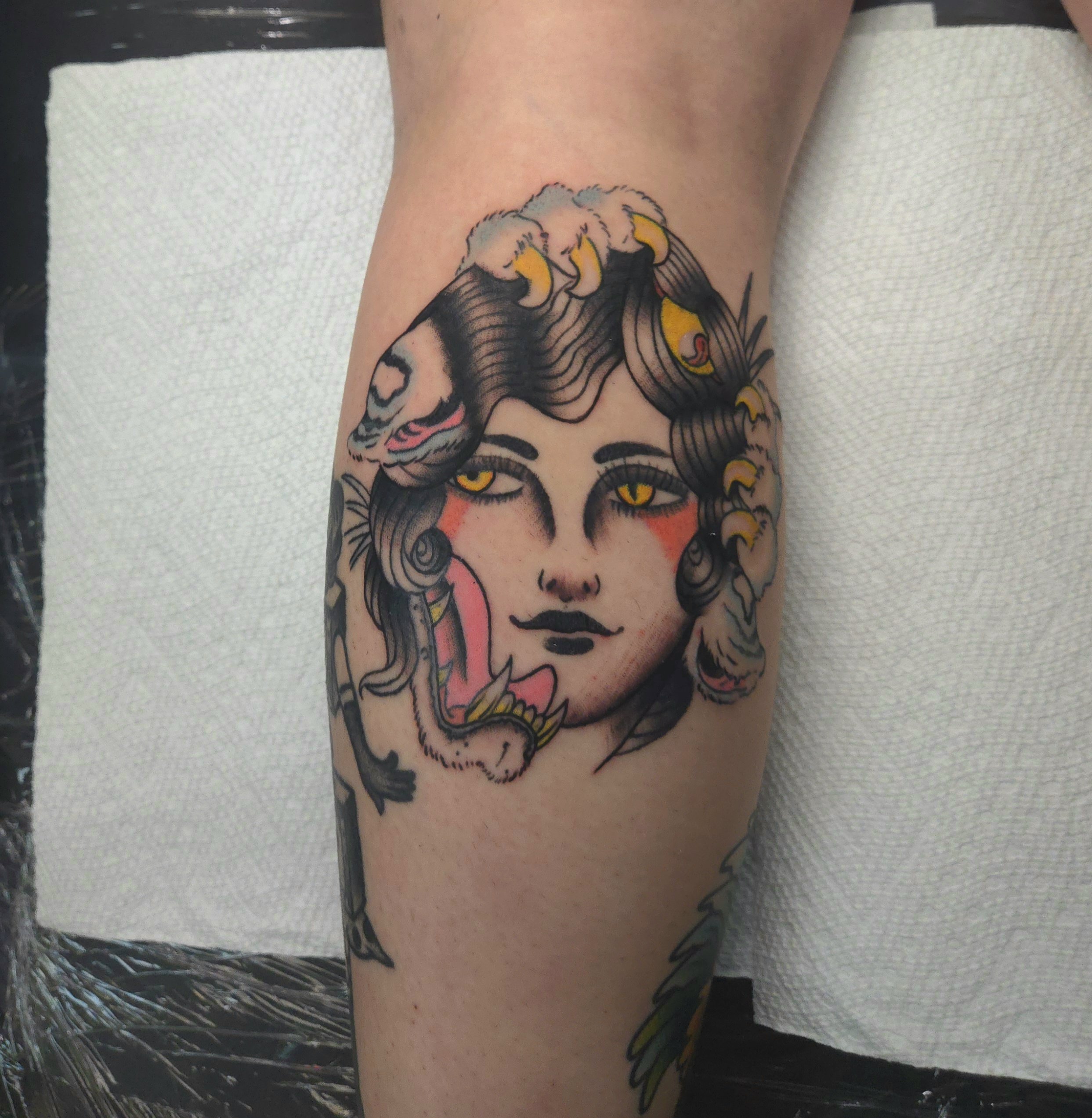 Color traditional calf tattoo featuring an Ed Hardy inspired morphed design combining a woman's face and a snarling tiger with bold linework and yellow eyes, custom tattoo by Brandon Perez at Big Kahuna Tattoo in Boca Raton, FL
