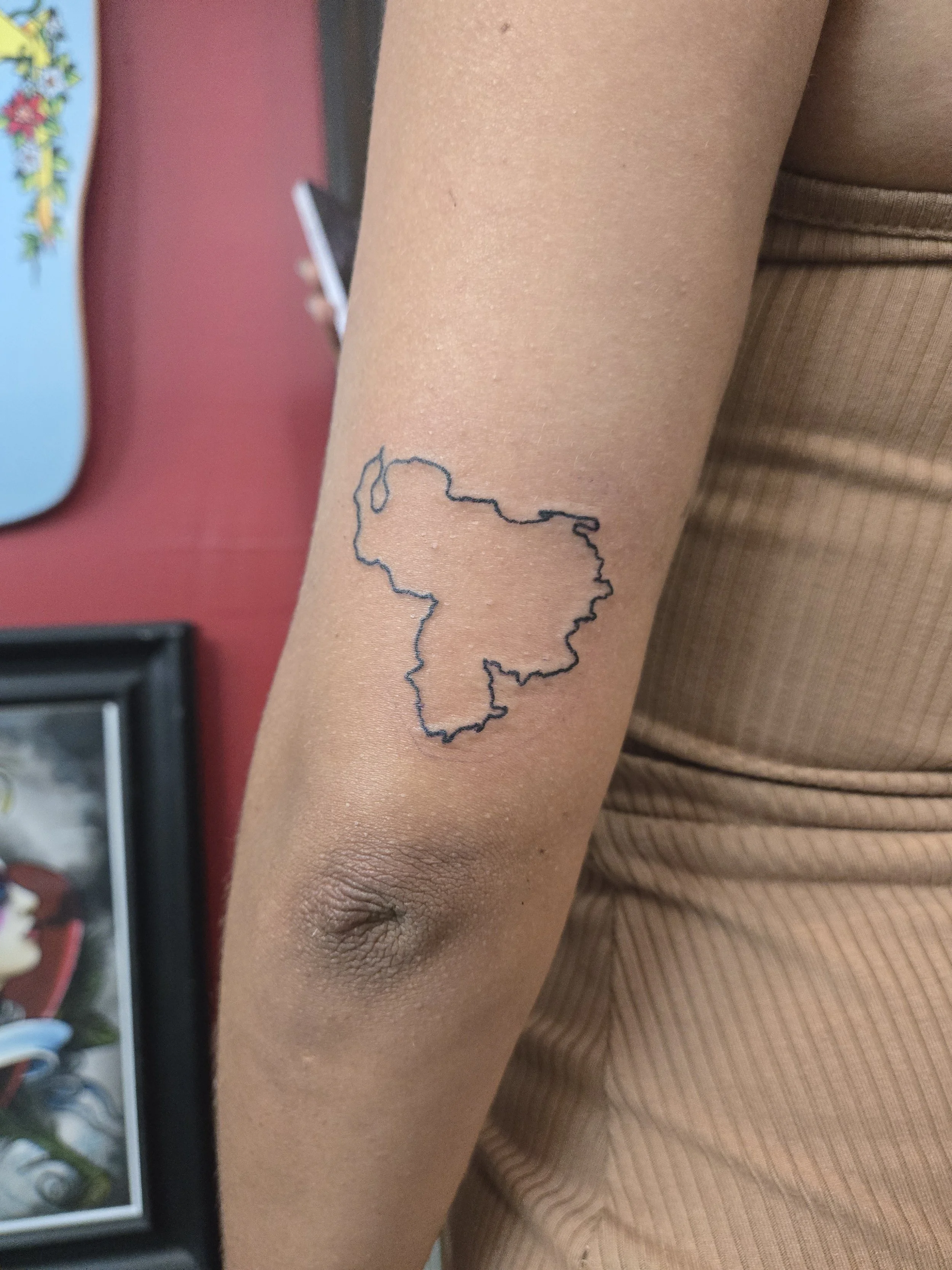 Fine line forearm tattoo featuring a minimalist outline of the country of Venezuela, custom heritage tattoo by Brandon Perez at Big Kahuna Tattoo in Boca Raton, FL