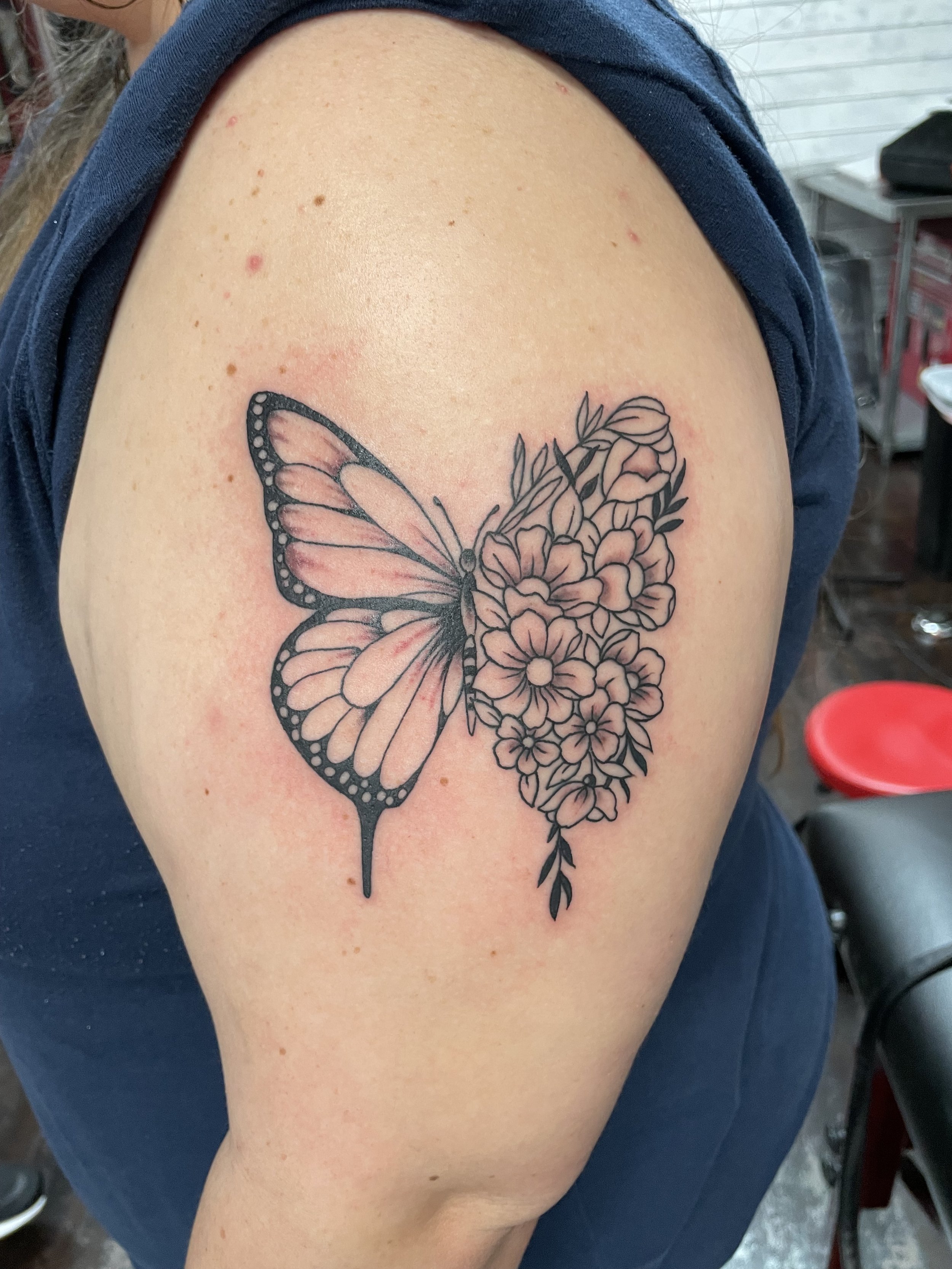 Fine line shoulder tattoo featuring a split-design butterfly with one natural wing and one wing composed entirely of clustered fine line flowers and leaves, custom tattoo by Nick at Big Kahuna Tattoo in Boca Raton, FL.