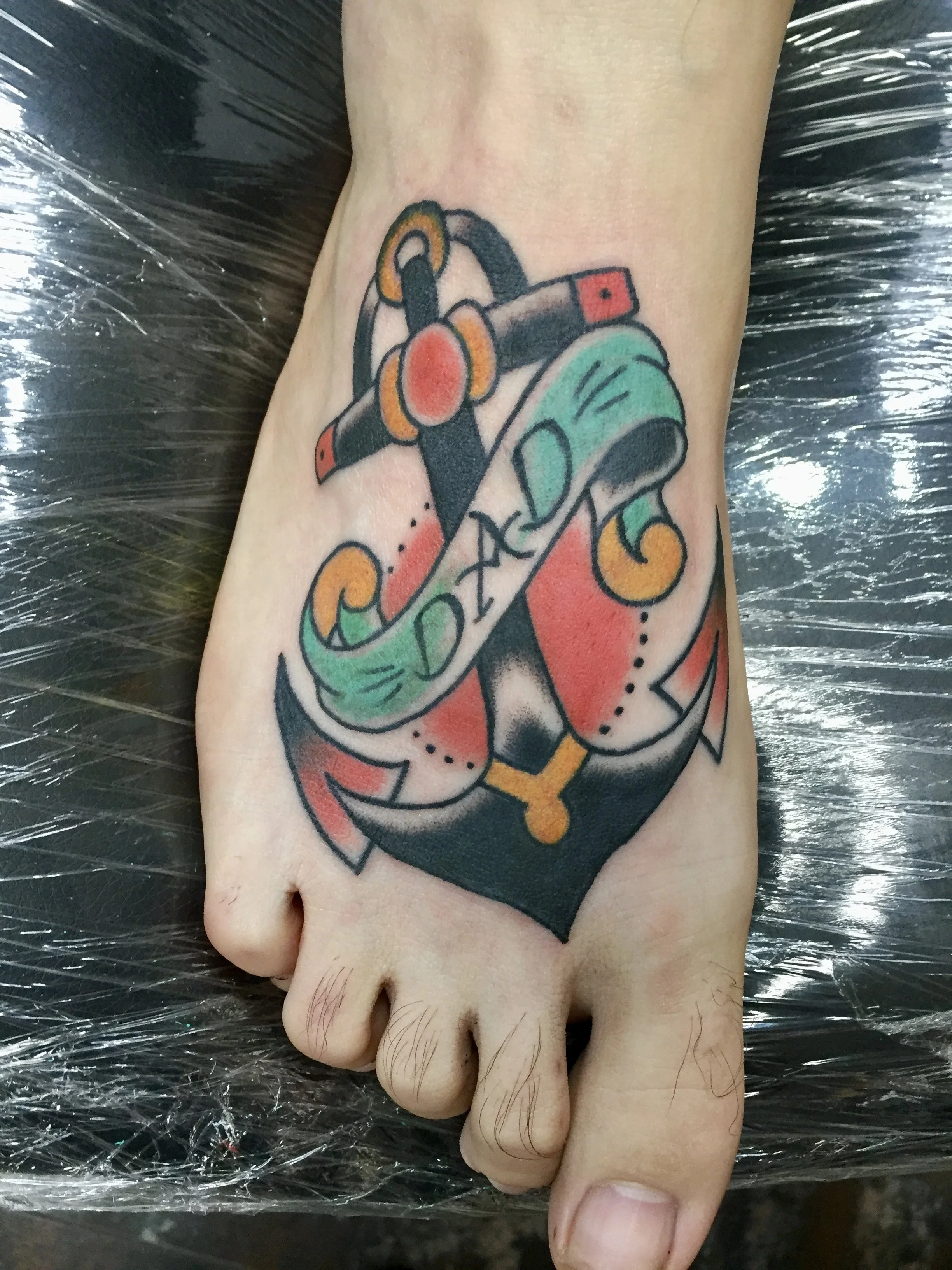 Traditional American color tattoo featuring a bold anchor with a decorative banner on the foot, custom tattoo by Nick at Big Kahuna Tattoo in Boca Raton, FL.
