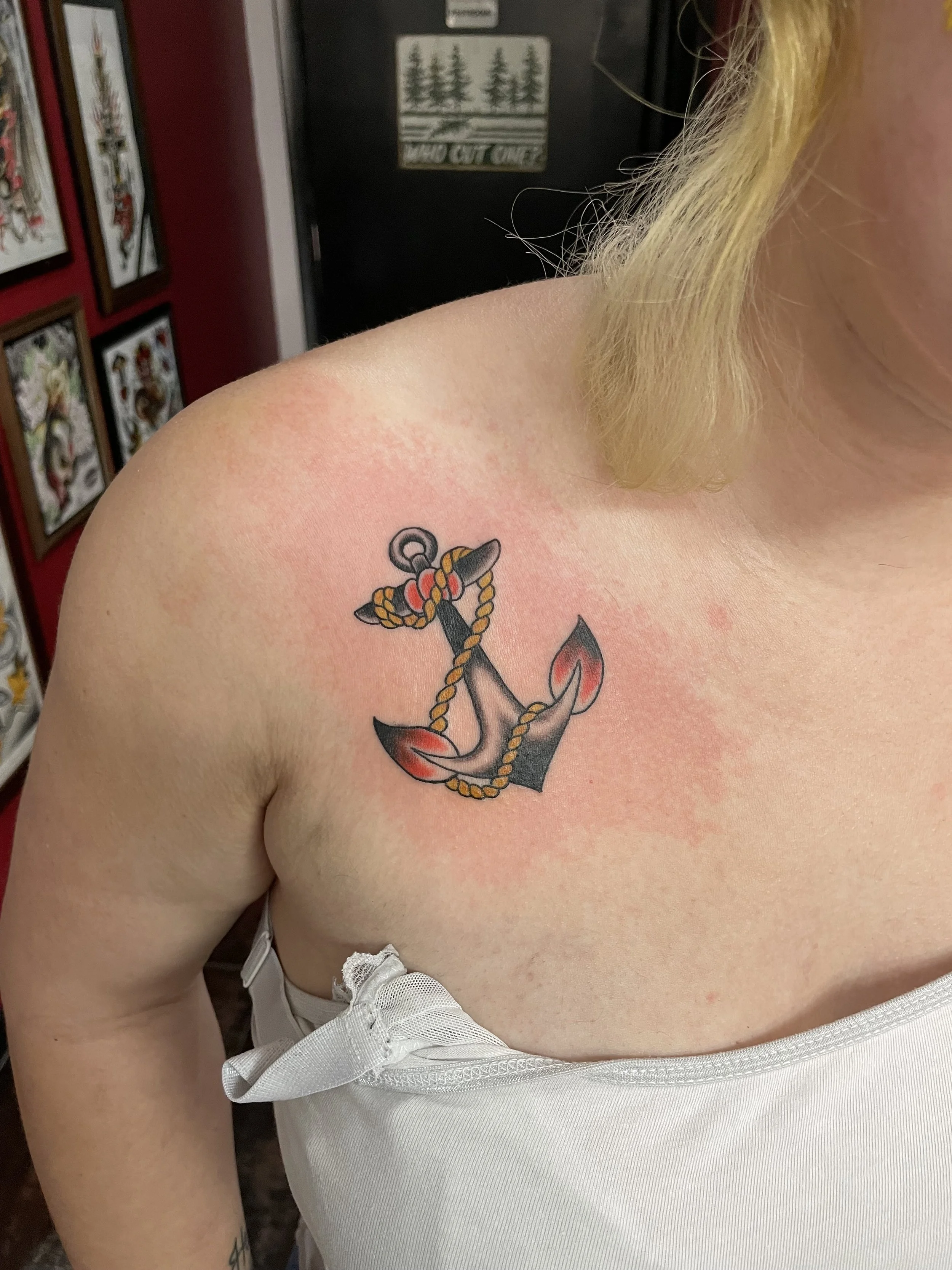 Classic traditional American black and grey collarbone tattoo featuring a nautical anchor wrapped with a gold twisted rope and red accent shading, custom tattoo by Nick at Big Kahuna Tattoo in Boca Raton, FL.