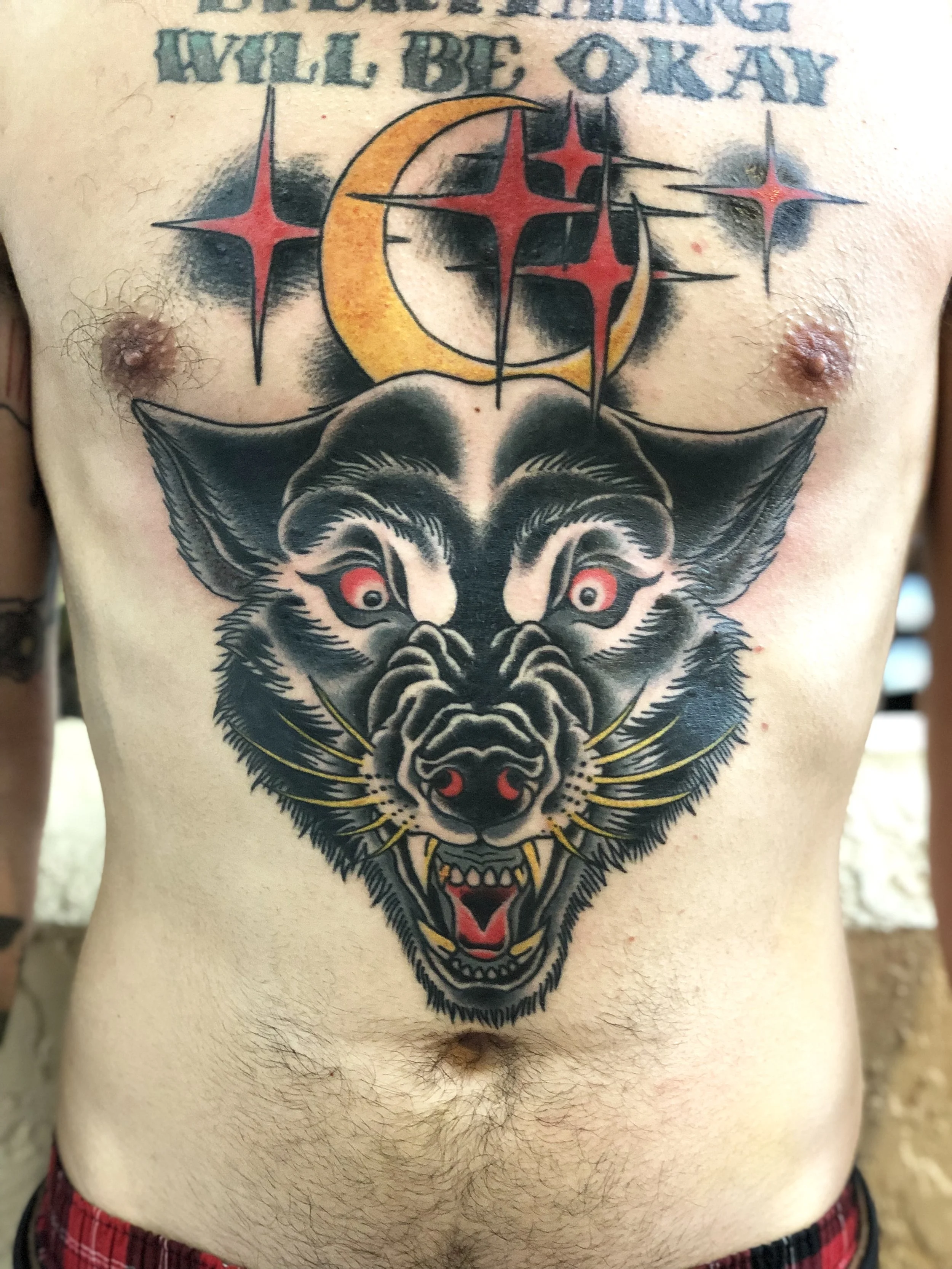 Large traditional American color stomach tattoo featuring a snarling werewolf head with red eyes beneath a gold crescent moon and red nautical stars, custom tattoo by Nick at Big Kahuna Tattoo in Boca Raton, FL.