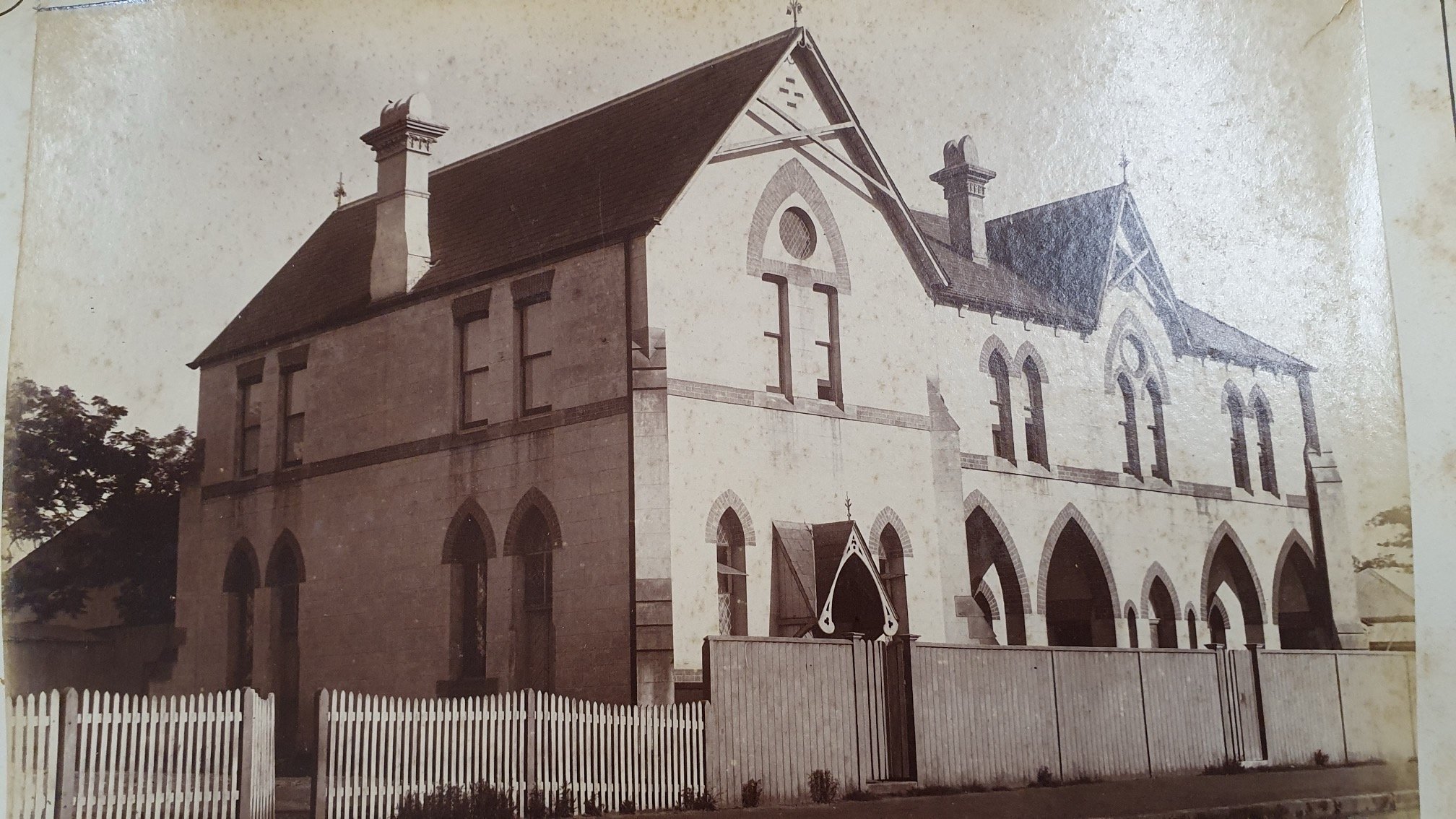Sepia-toned vintage photograph of a large two-story Gothic Revival-style building, possibly a former convent, school, or institutional residence, characterized by pointed arch windows, steep gabled roofs, and decorative crosses atop the peaks.