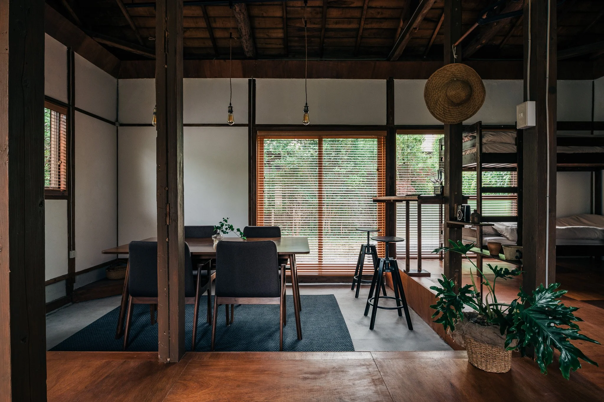 木製の家具と緑の観葉植物が置かれた、自然光が差し込むシンプルなリビングルームのインテリア